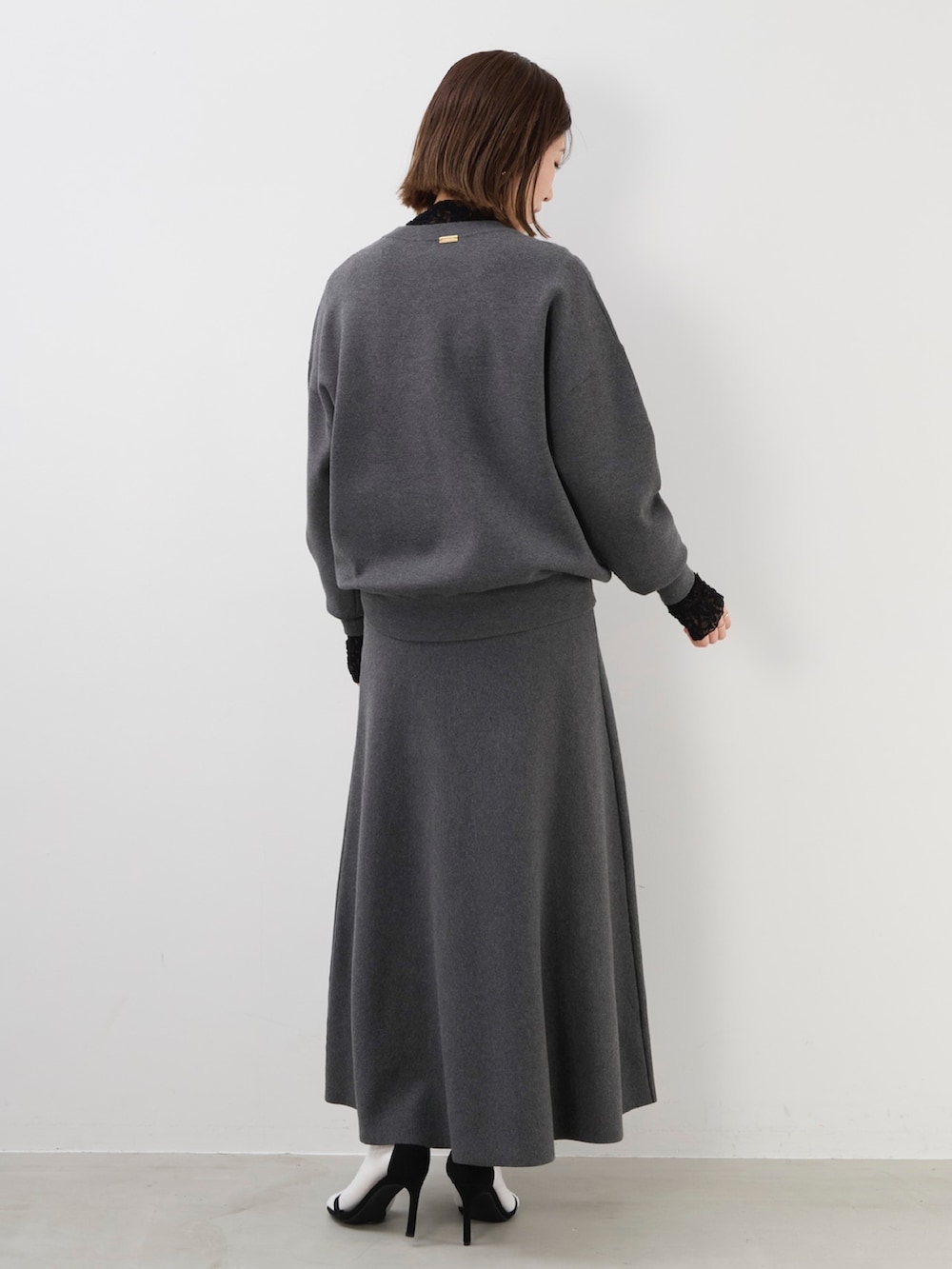 グレー系のニット/セーター、グレー系のスカート、ブラック系のTシャツ/カットソーを着用したレディースの秋コーディネートの7枚目の写真