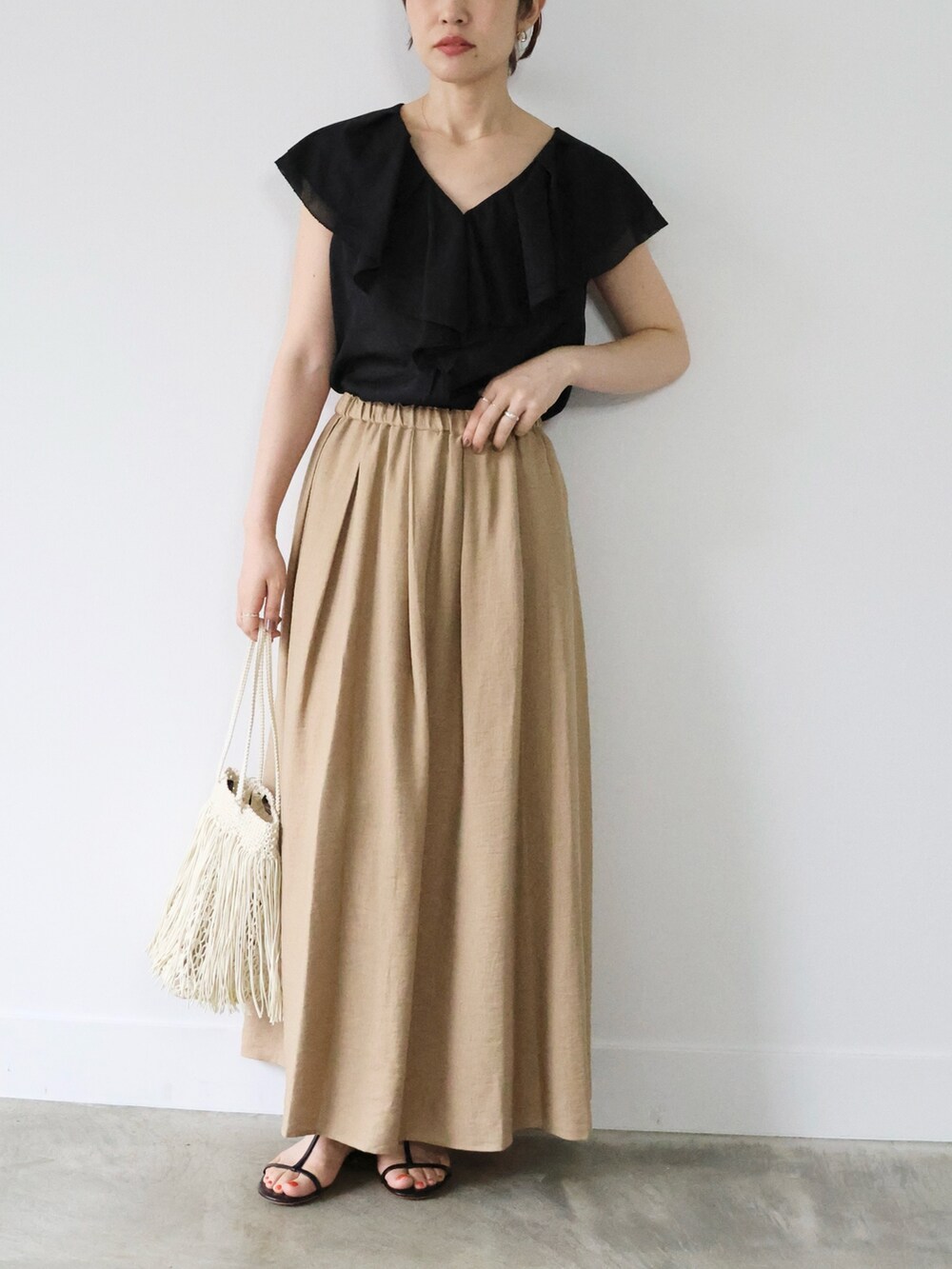 ブラック系のシャツ/ブラウス、ベージュ系のスカート、ブラック系のサンダルを着用したレディースの夏コーディネートの2枚目の写真