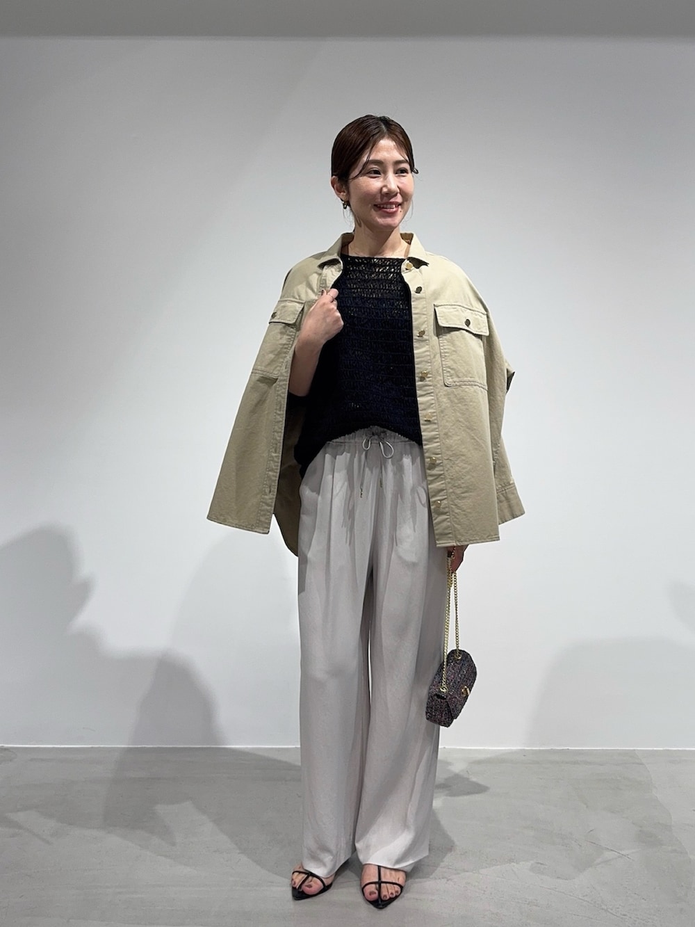 ベージュ系のシャツ/ブラウス、ブラック系のニット/セーター、その他のショルダーバッグを着用したレディースの春コーディネートの2枚目の写真