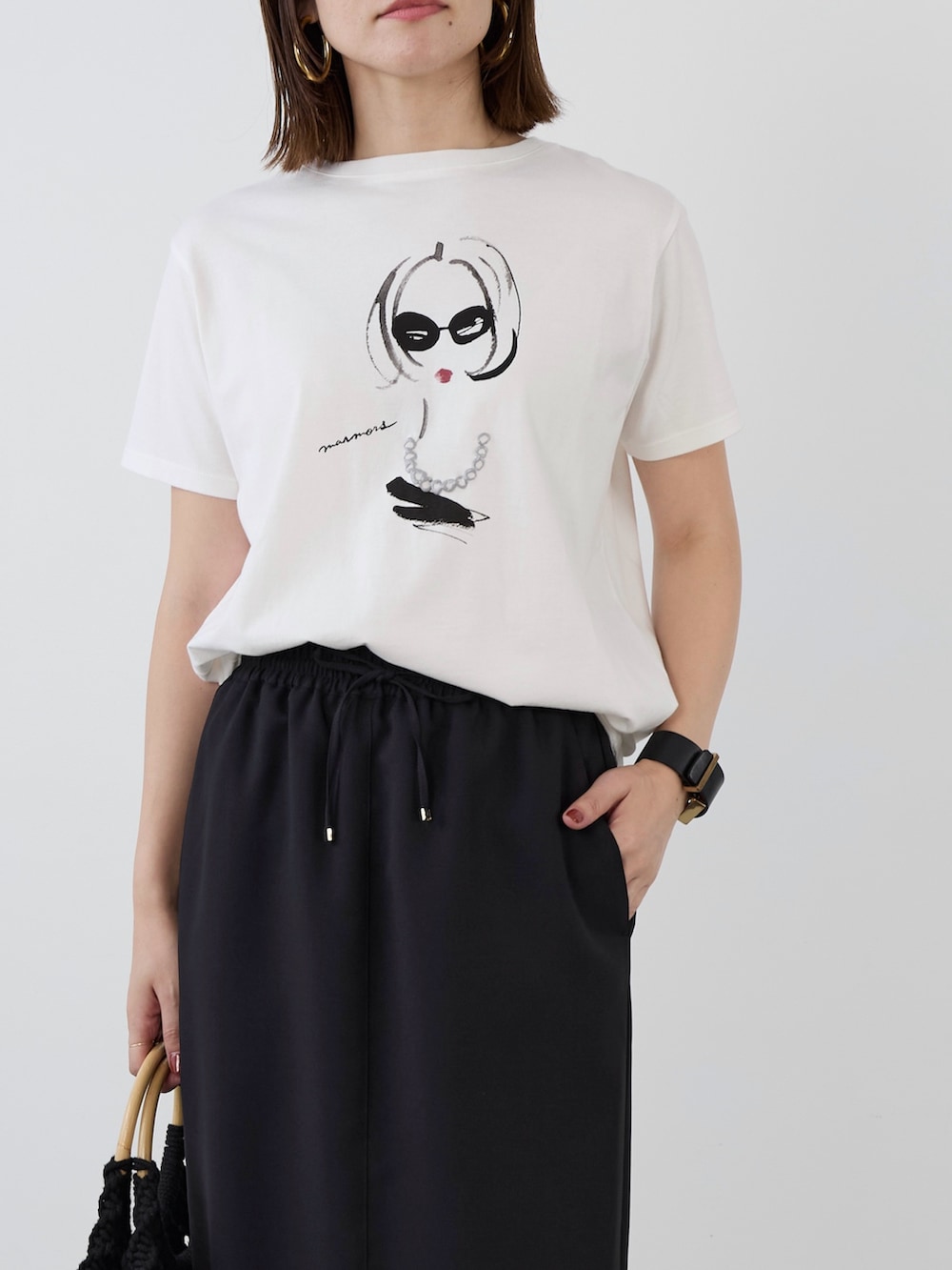 ホワイト系のTシャツ/カットソー、ブラック系のスカートを着用したレディースの春コーディネートの2枚目の写真