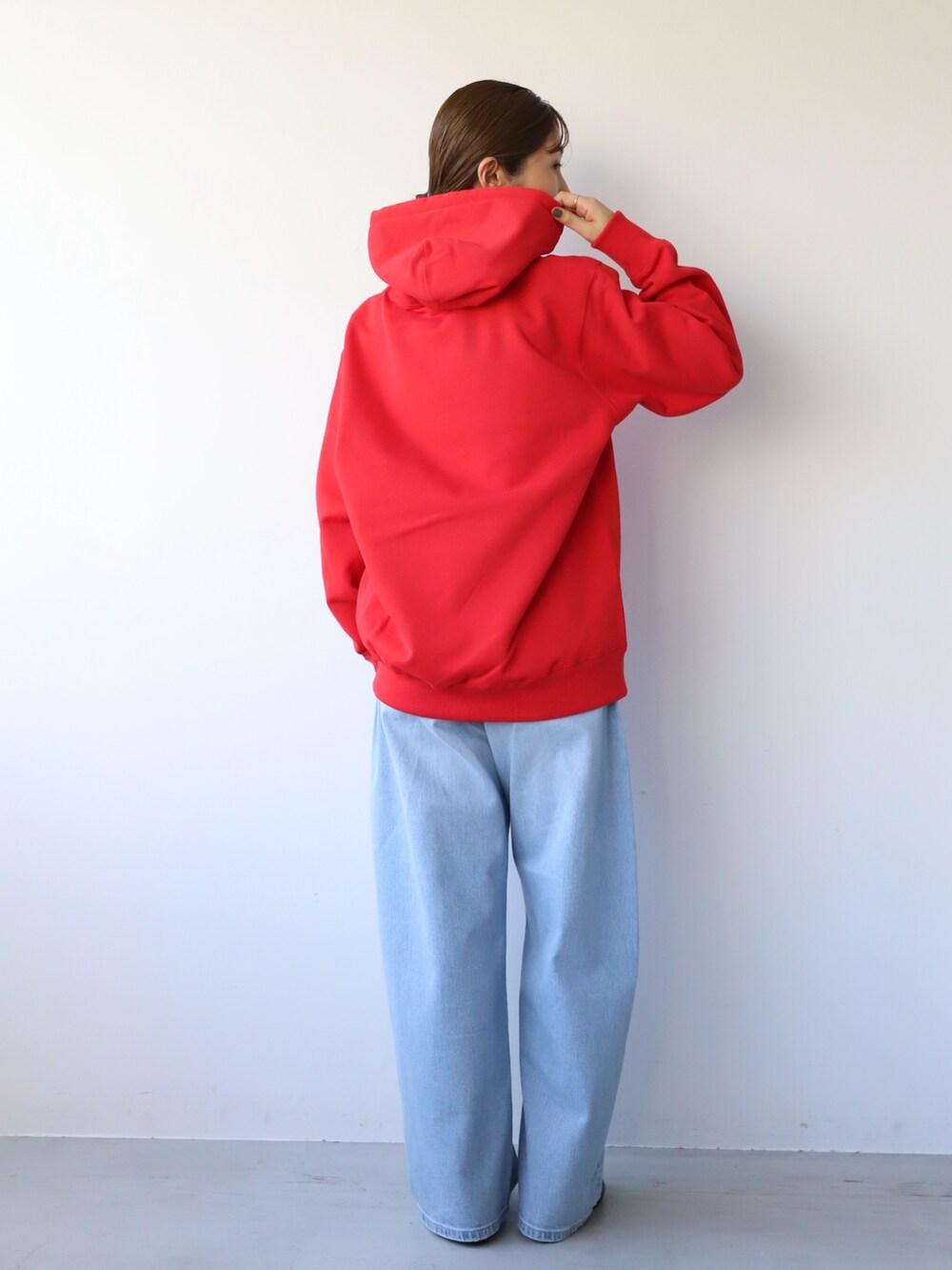 ブルー系のデニムパンツ、ブラック系のバレエシューズ、レッド系のパーカーを着用したレディースの秋コーディネートの4枚目の写真