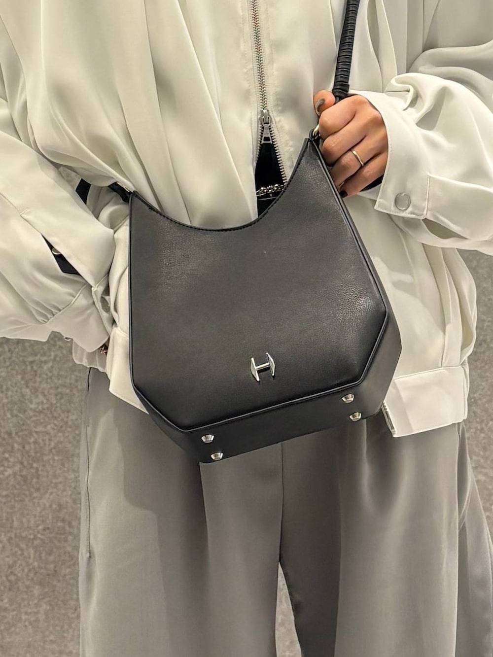 ブラック系のスニーカー、ホワイト系のブルゾン、グレー系のスラックスを着用したレディースの春コーディネートの4枚目の写真