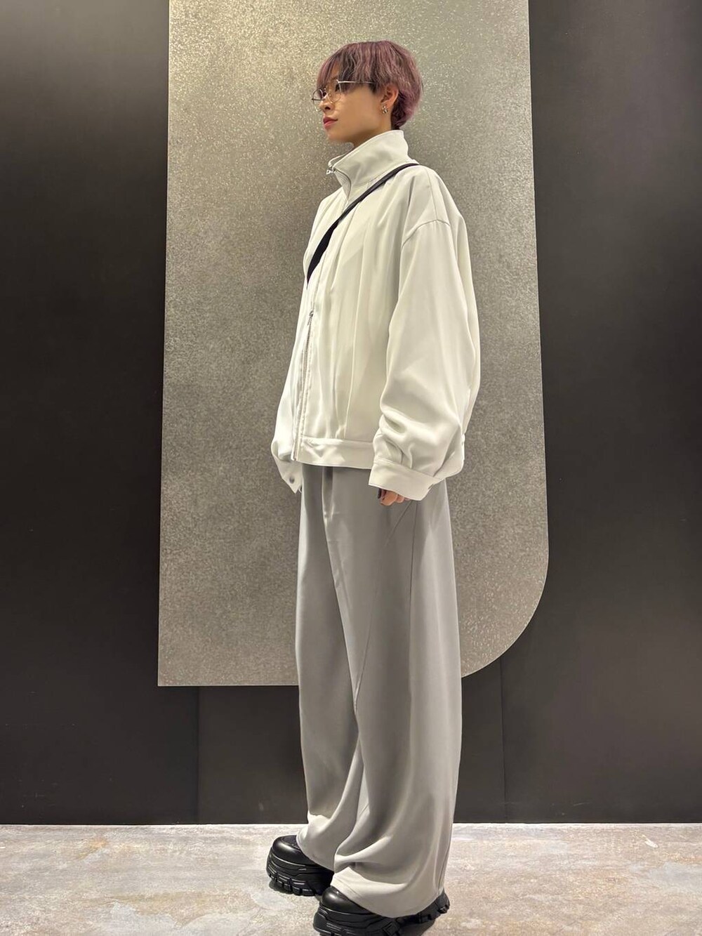 ブラック系のスニーカー、ホワイト系のブルゾン、グレー系のスラックスを着用したレディースの春コーディネートの2枚目の写真