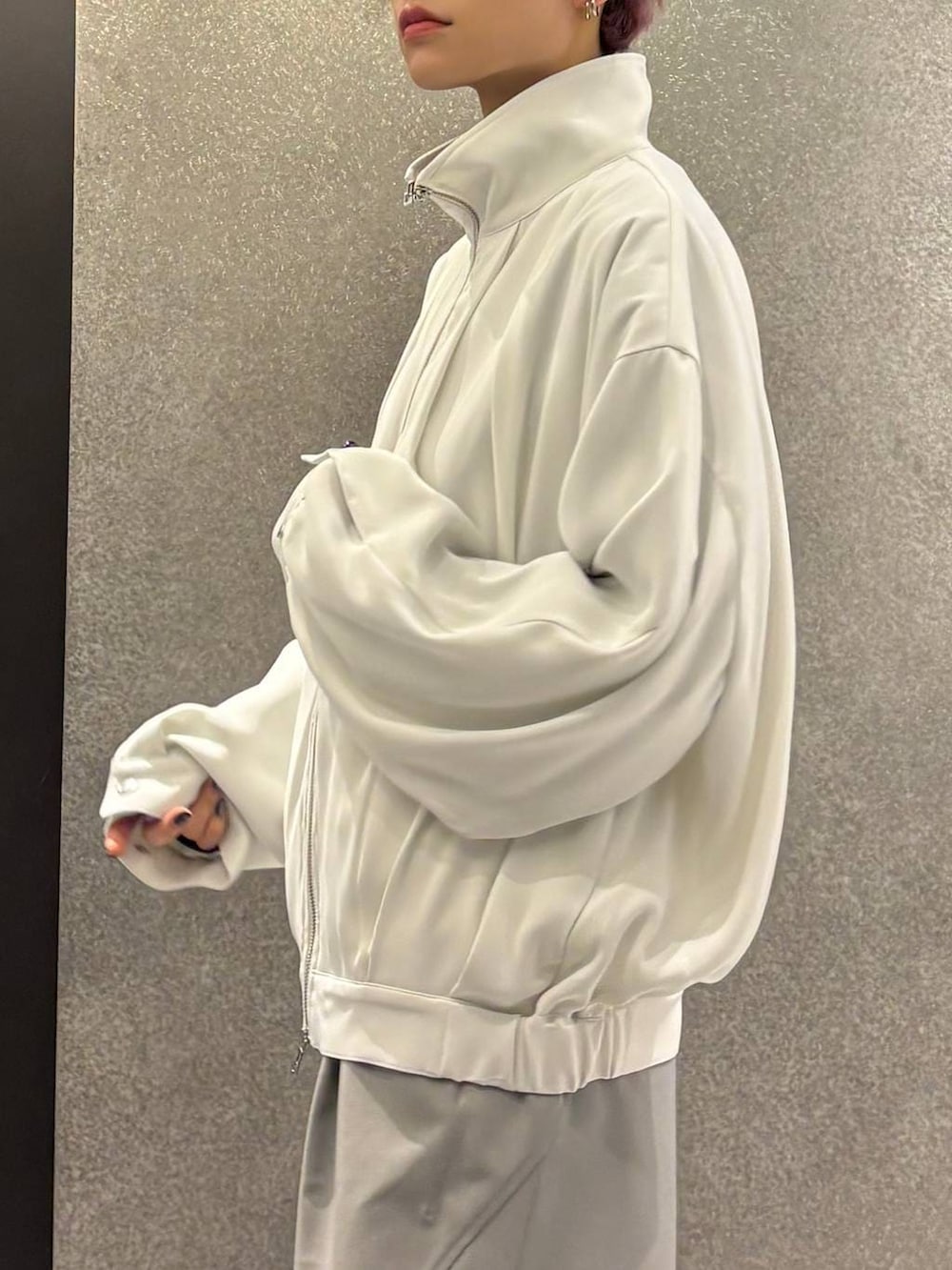 ブラック系のスニーカー、ホワイト系のブルゾン、グレー系のスラックスを着用したレディースの春コーディネートの7枚目の写真