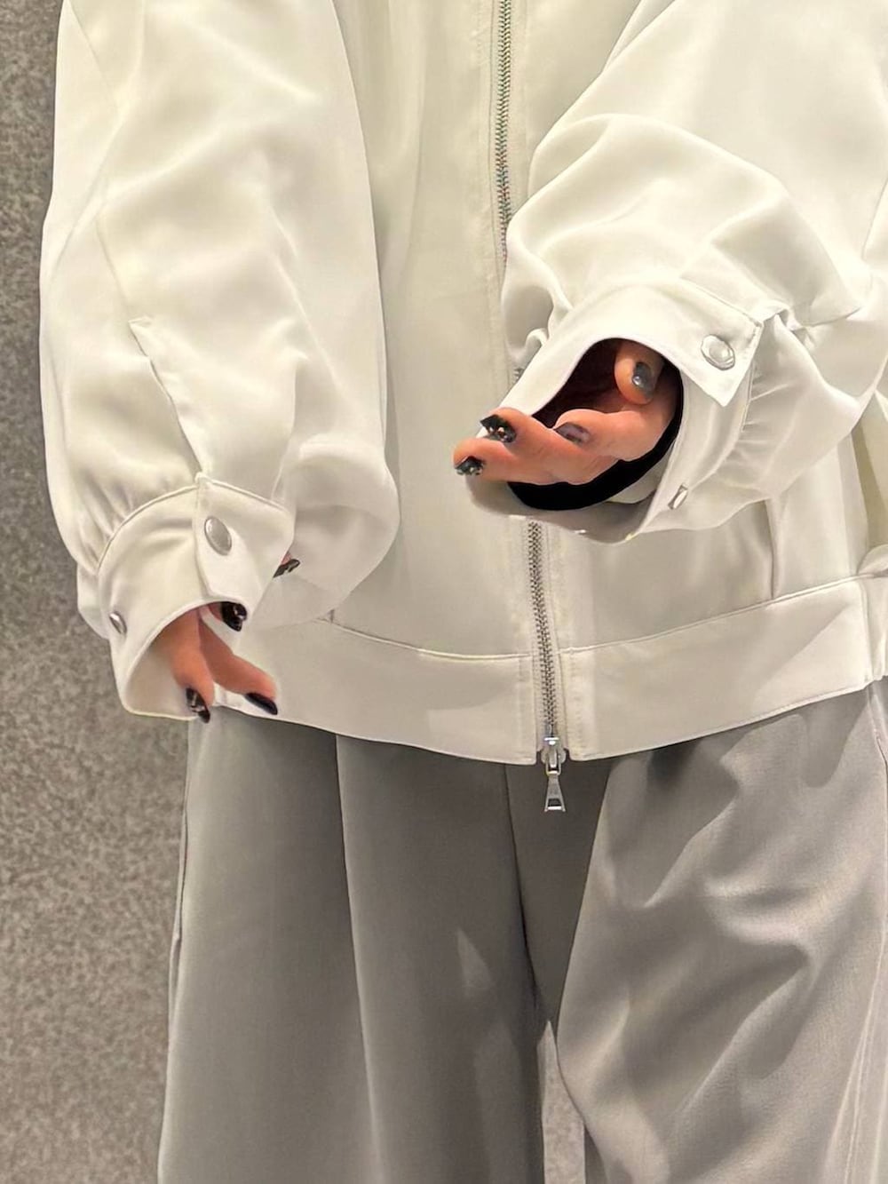 ブラック系のスニーカー、ホワイト系のブルゾン、グレー系のスラックスを着用したレディースの春コーディネートの6枚目の写真