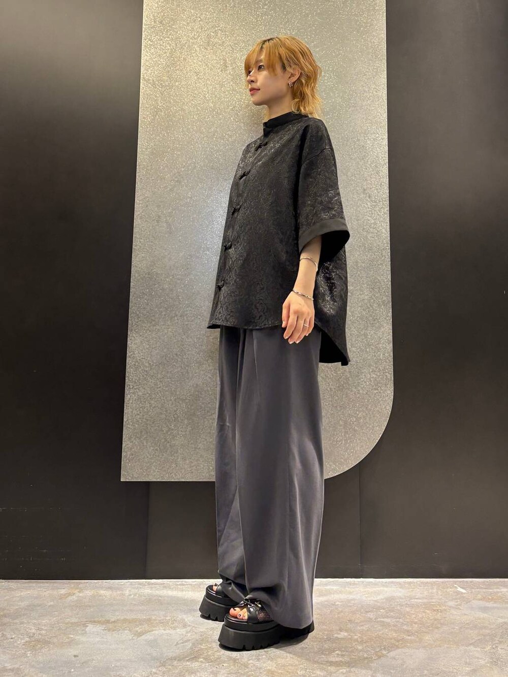ブラック系のサンダル、グレー系のスラックス、ブラック系のシャツ/ブラウスを着用したレディースの夏コーディネートの2枚目の写真