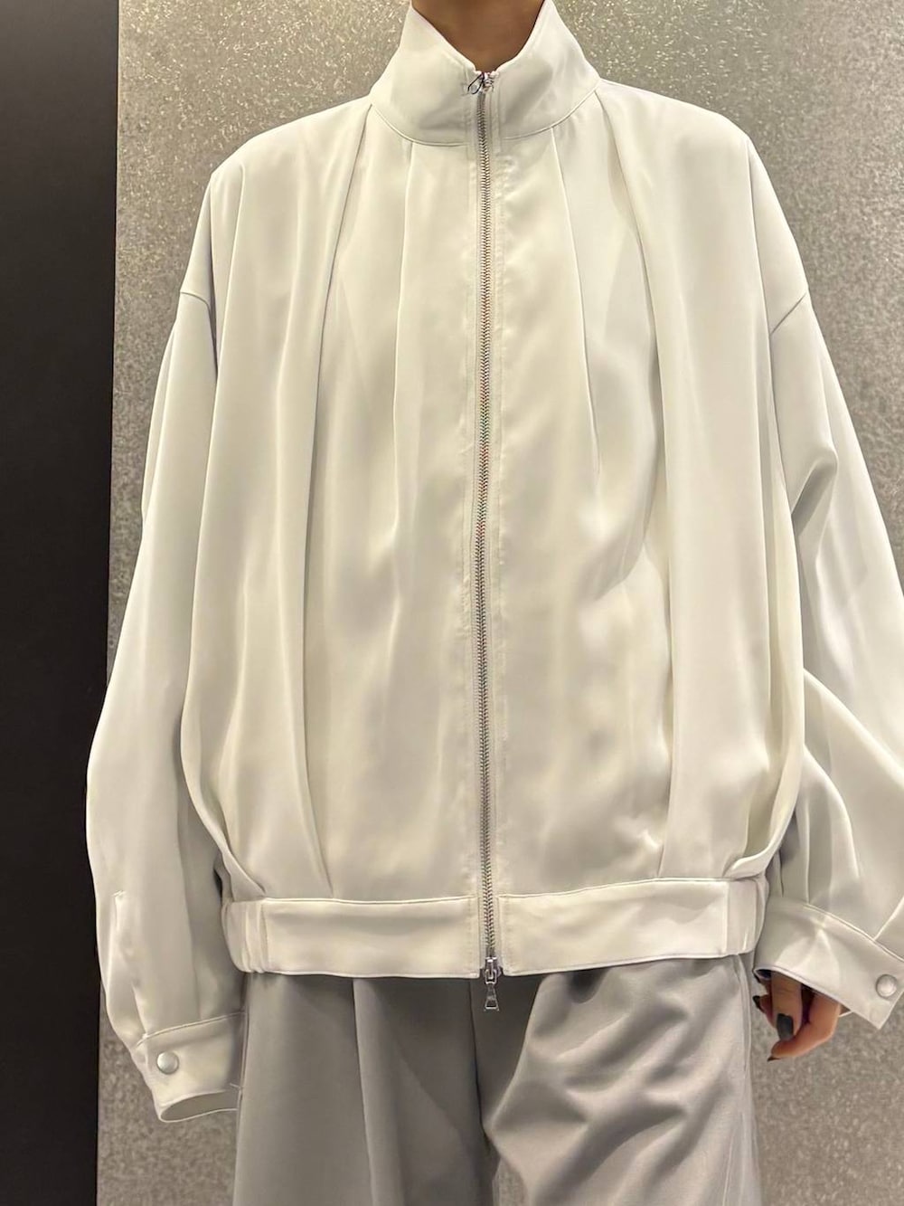 ブラック系のスニーカー、ホワイト系のブルゾン、グレー系のスラックスを着用したレディースの春コーディネートの5枚目の写真