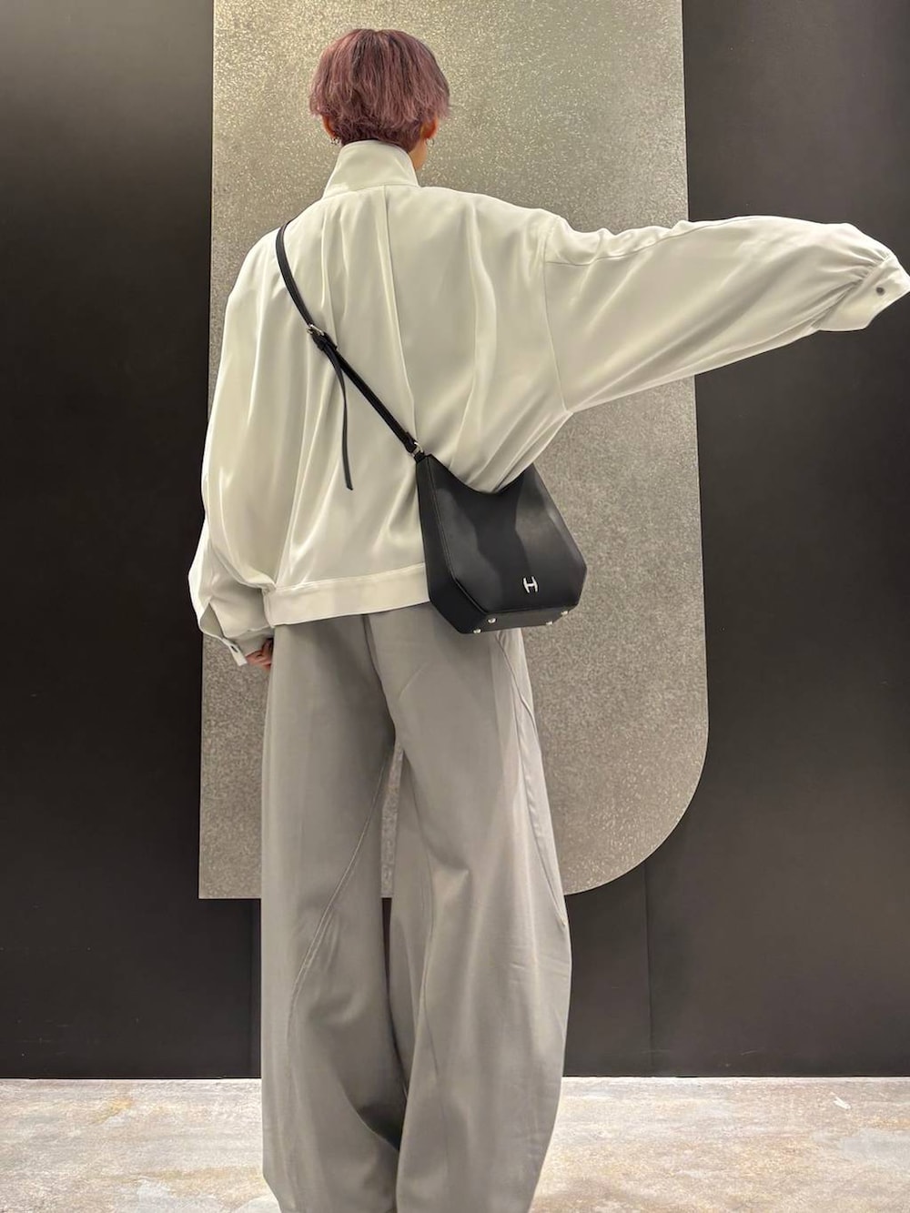 ブラック系のスニーカー、ホワイト系のブルゾン、グレー系のスラックスを着用したレディースの春コーディネートの3枚目の写真