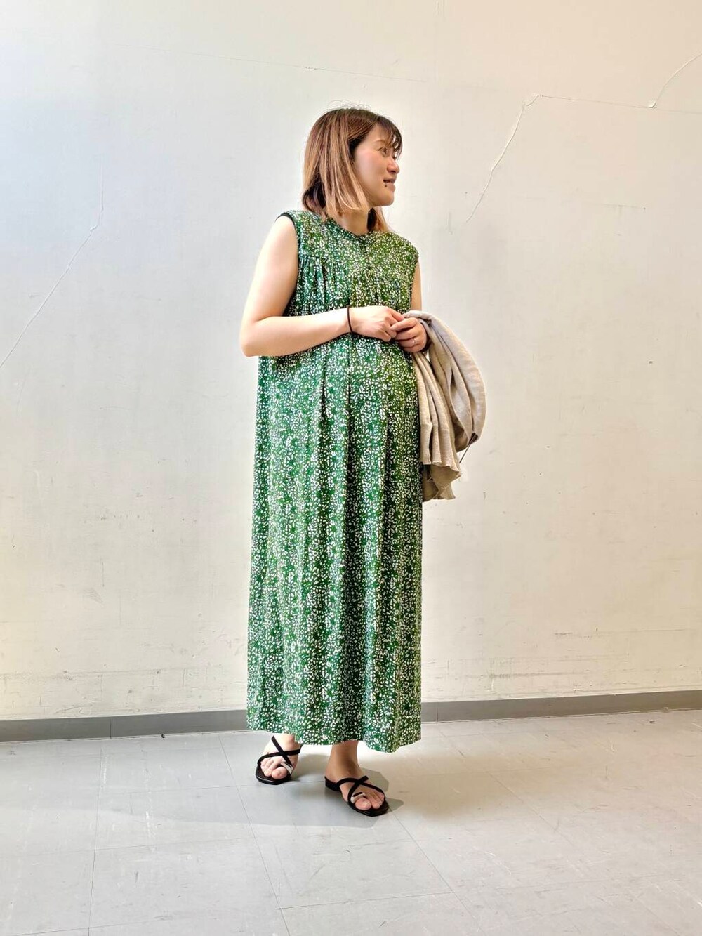 ベージュ系のカーディガン/ボレロ、グリーン系のワンピース、ブラック系のサンダルを着用したレディースの夏コーディネートの5枚目の写真