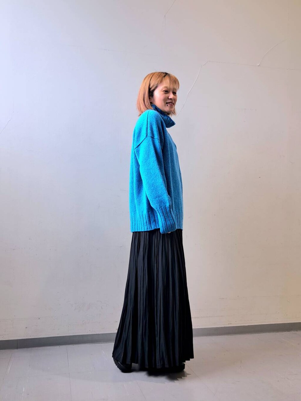 ブラック系のブーツ、ブラック系のスカート、ブルー系のニット/セーターを着用したレディースの秋コーディネートの2枚目の写真