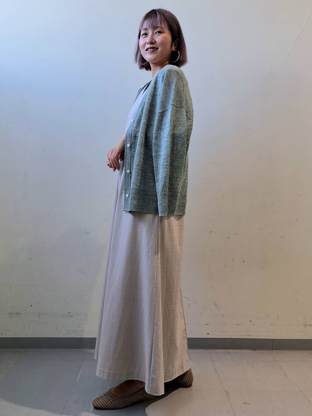 グリーン系のカーディガン/ボレロ、ベージュ系のパンプス、グレー系のワンピースを着用したレディースの夏コーディネートの3枚目の写真