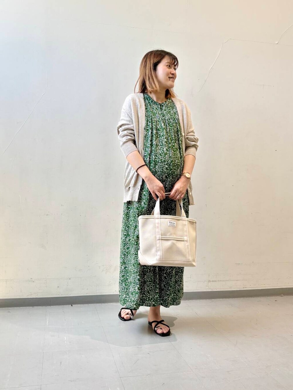 ベージュ系のカーディガン/ボレロ、グリーン系のワンピース、ブラック系のサンダルを着用したレディースの夏コーディネートの2枚目の写真