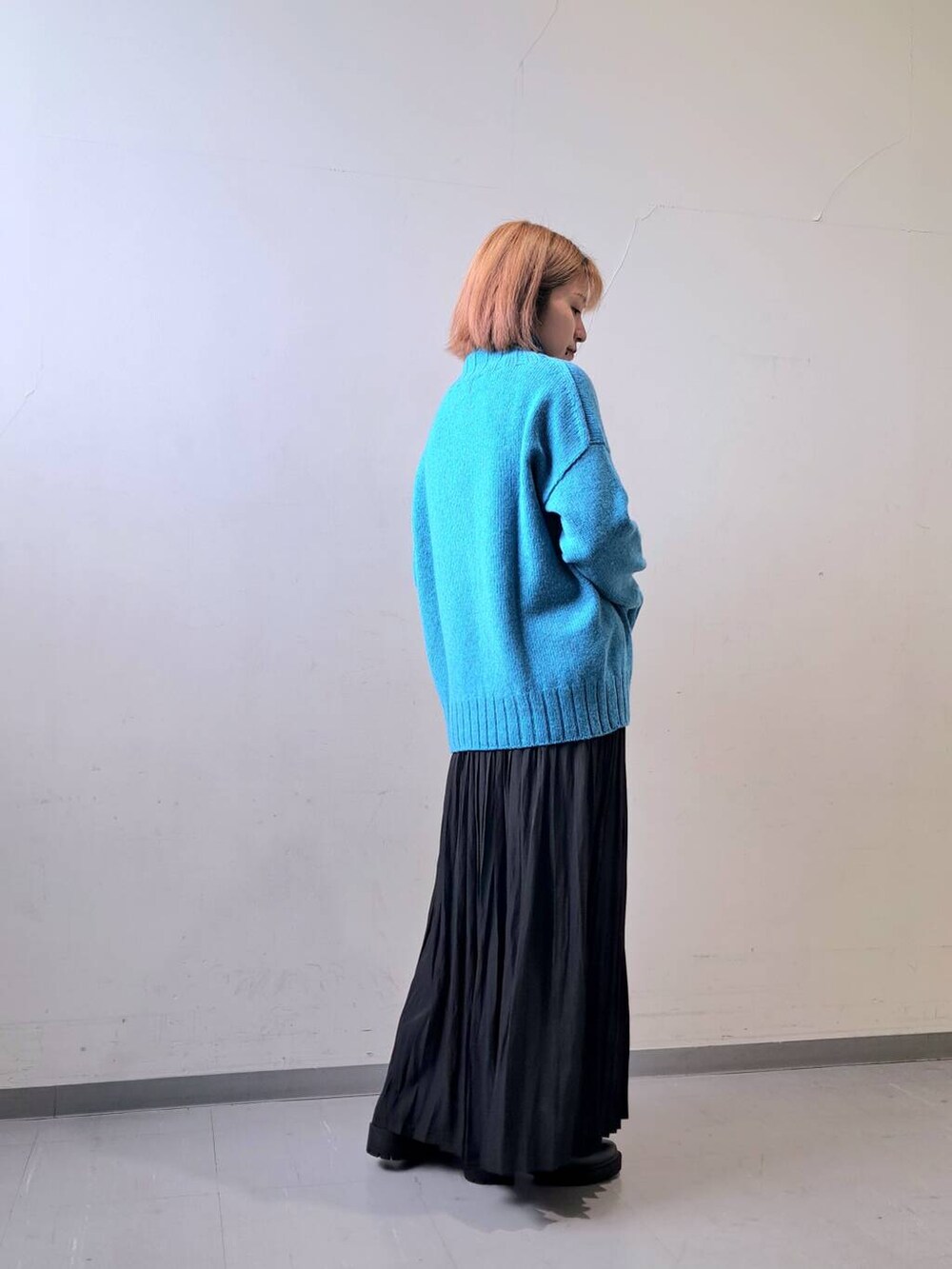 ブラック系のブーツ、ブラック系のスカート、ブルー系のニット/セーターを着用したレディースの秋コーディネートの4枚目の写真