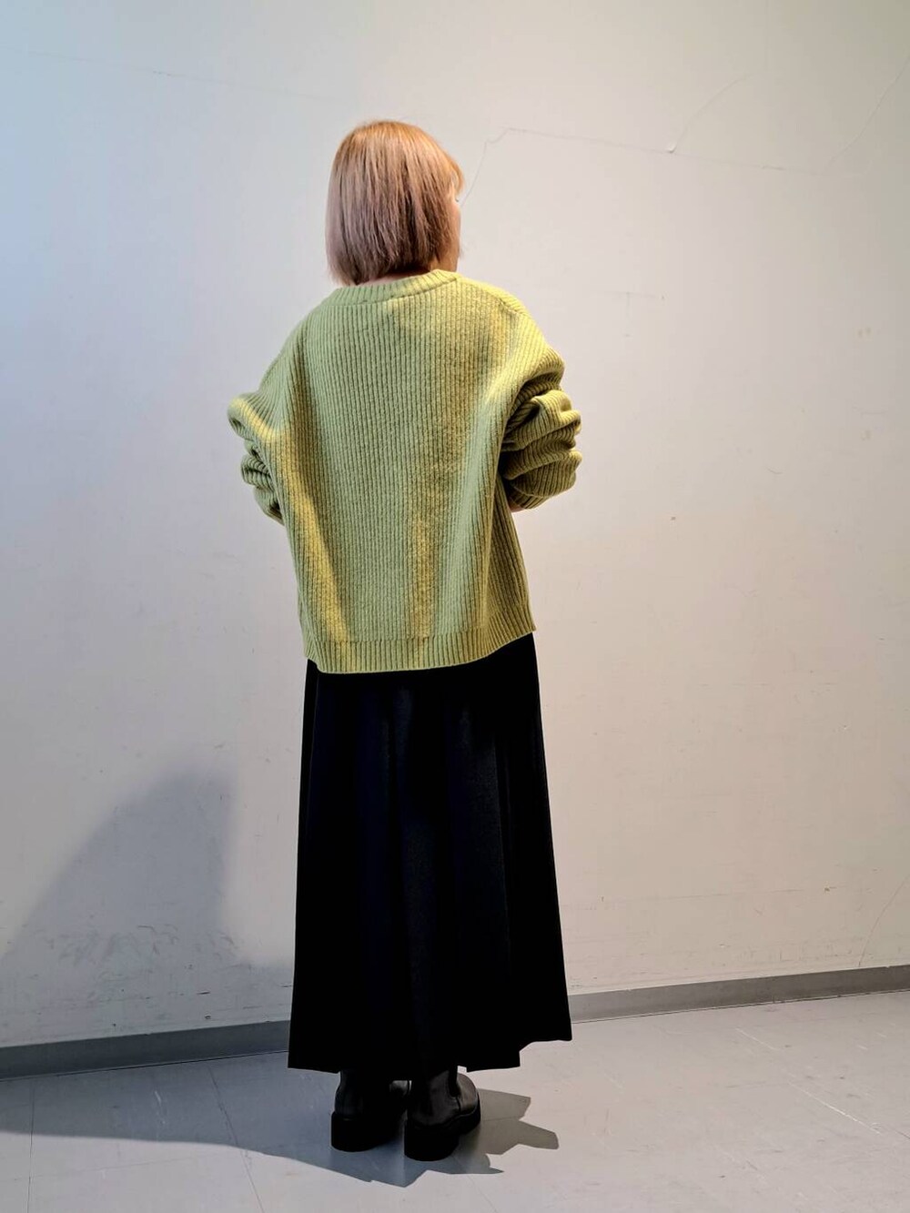 グリーン系のカーディガン/ボレロ、ブラウン系のブーツ、ブラック系のスカートを着用したレディースの秋コーディネートの3枚目の写真