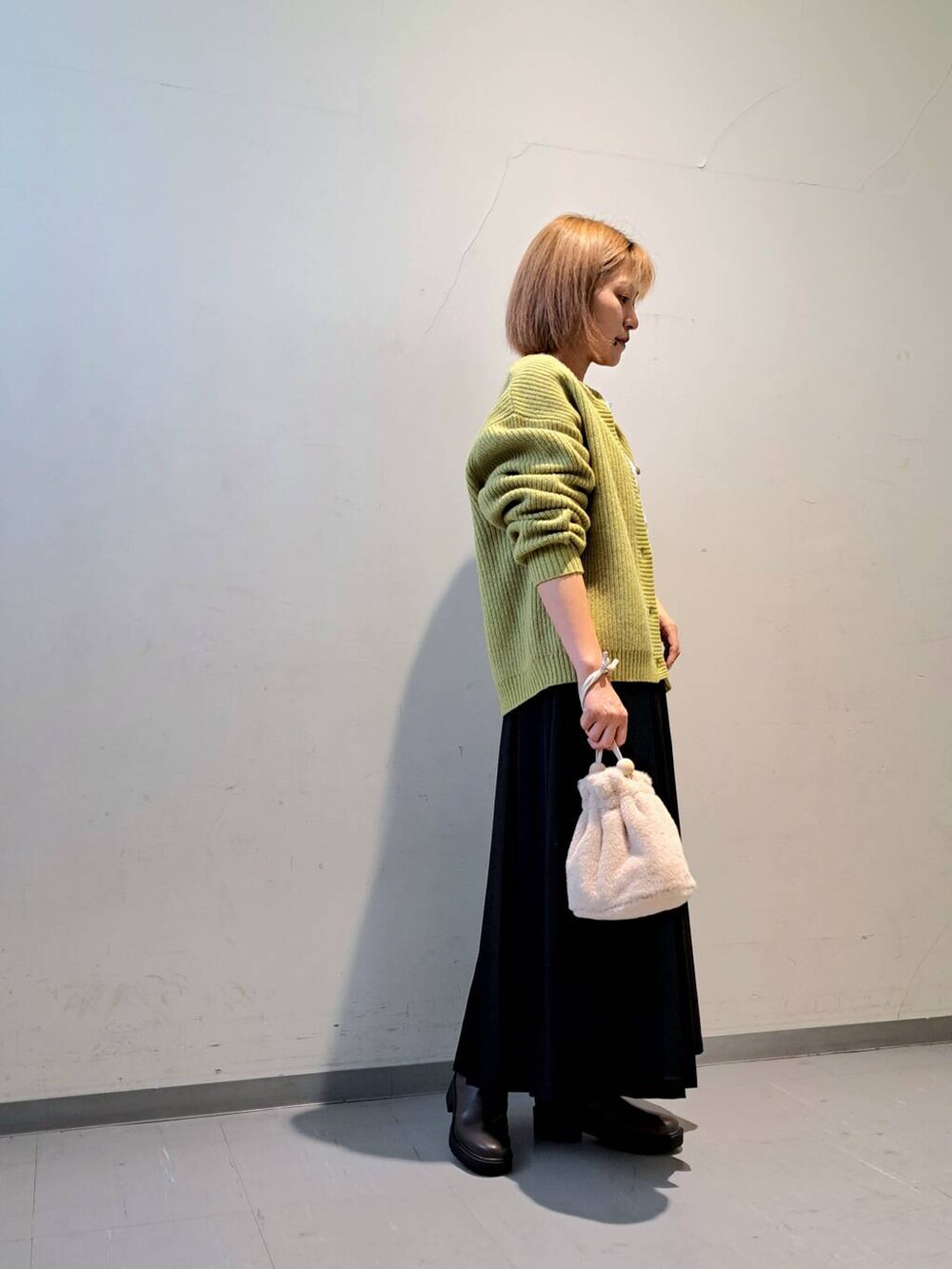 グリーン系のカーディガン/ボレロ、ブラウン系のブーツ、ブラック系のスカートを着用したレディースの秋コーディネートの2枚目の写真