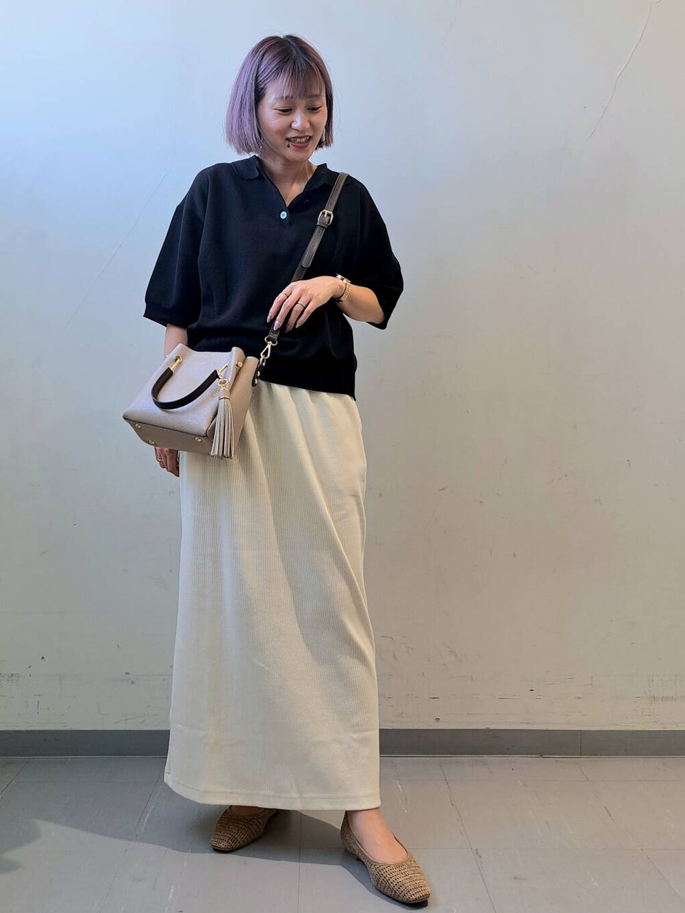 ベージュ系のトートバッグ、ベージュ系のパンプス、ホワイト系のスカートを着用したレディースの夏コーディネートの2枚目の写真