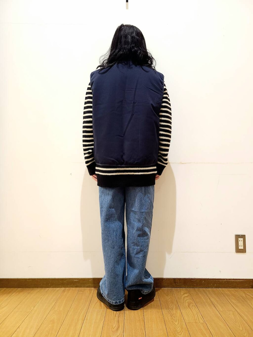 ブルー系のダウンベスト、ブルー系のデニムパンツ、ブラック系のニット/セーターを着用したメンズの冬コーディネートの3枚目の写真