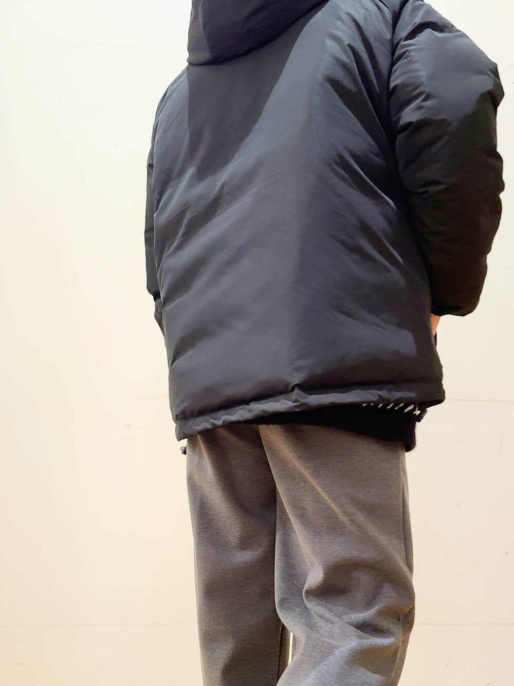 グレー系のその他パンツ、ブラック系のニット/セーター、ブラック系のダウンジャケット/コートを着用したメンズの冬コーディネートの8枚目の写真