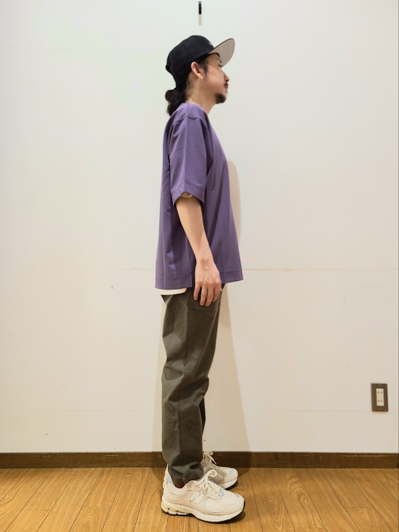 パープル系のTシャツ/カットソー、グリーン系のその他パンツ、ブラック系のキャップを着用したメンズの春コーディネートの2枚目の写真