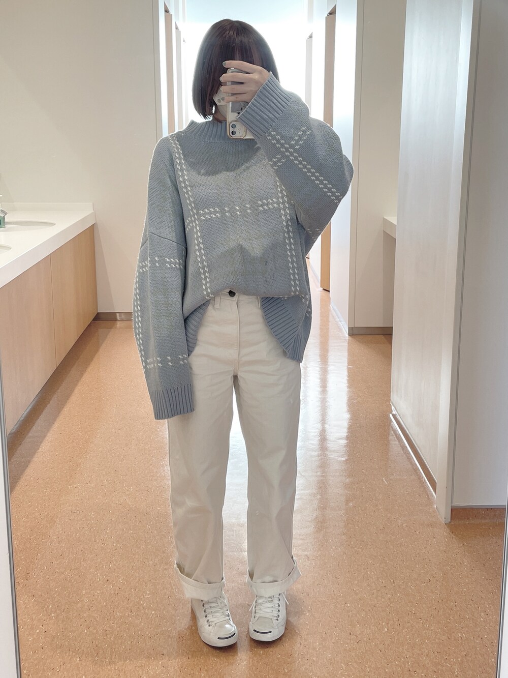 ホワイト系のデニムパンツ、ブルー系のニット/セーター、ホワイト系のスニーカーを着用したレディースの冬コーディネートの2枚目の写真