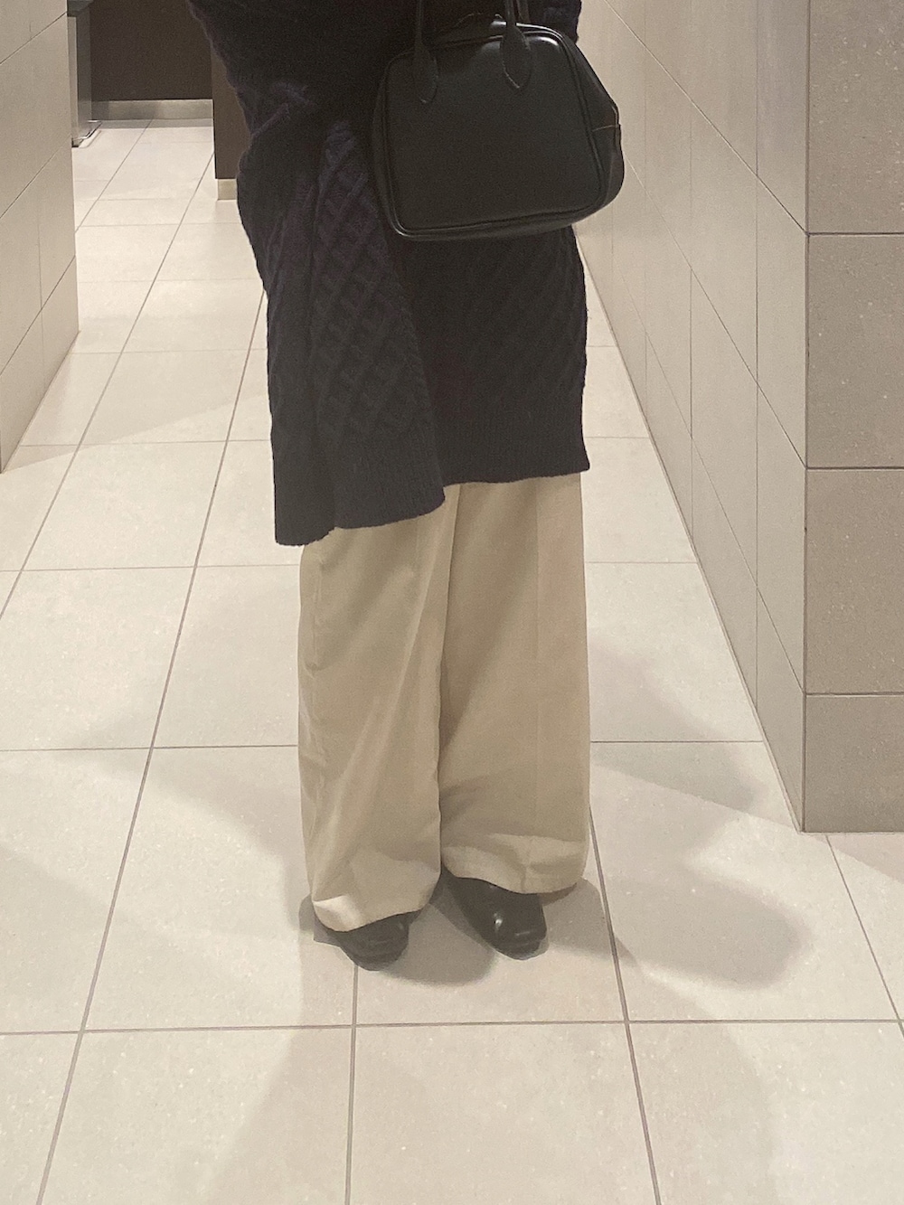 ブルー系のニット/セーター、ブラック系のボストンバッグ、ホワイト系のスラックスを着用したレディースの秋コーディネートの2枚目の写真