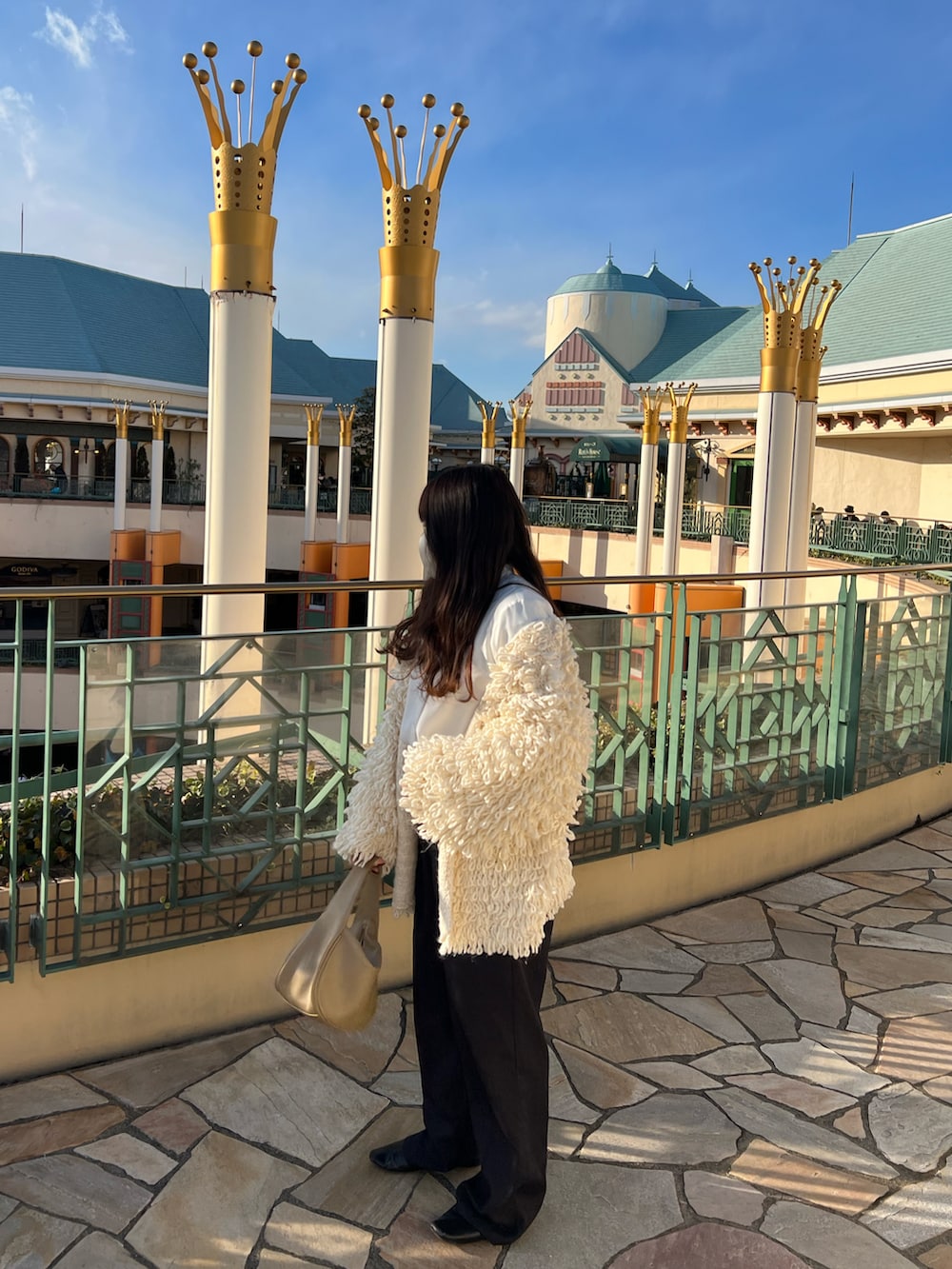 ホワイト系のカーディガン/ボレロ、ベージュ系のハンドバッグ、ブラック系のスラックスを着用したレディースの冬コーディネートの2枚目の写真