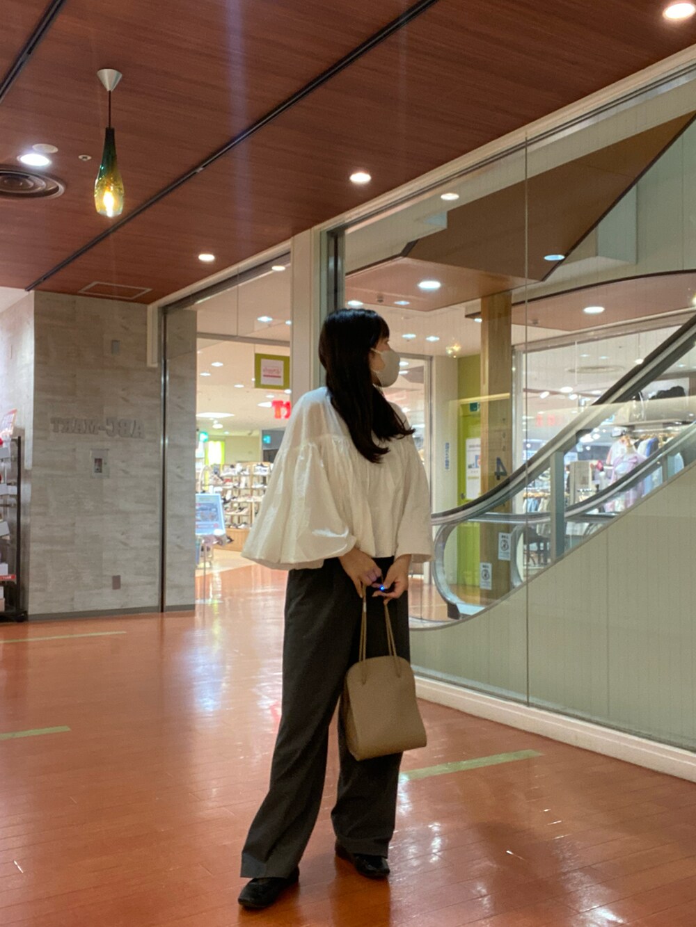 ホワイト系のシャツ/ブラウス、ベージュ系のトートバッグ、グレー系のスラックスを着用したレディースの春コーディネートの2枚目の写真