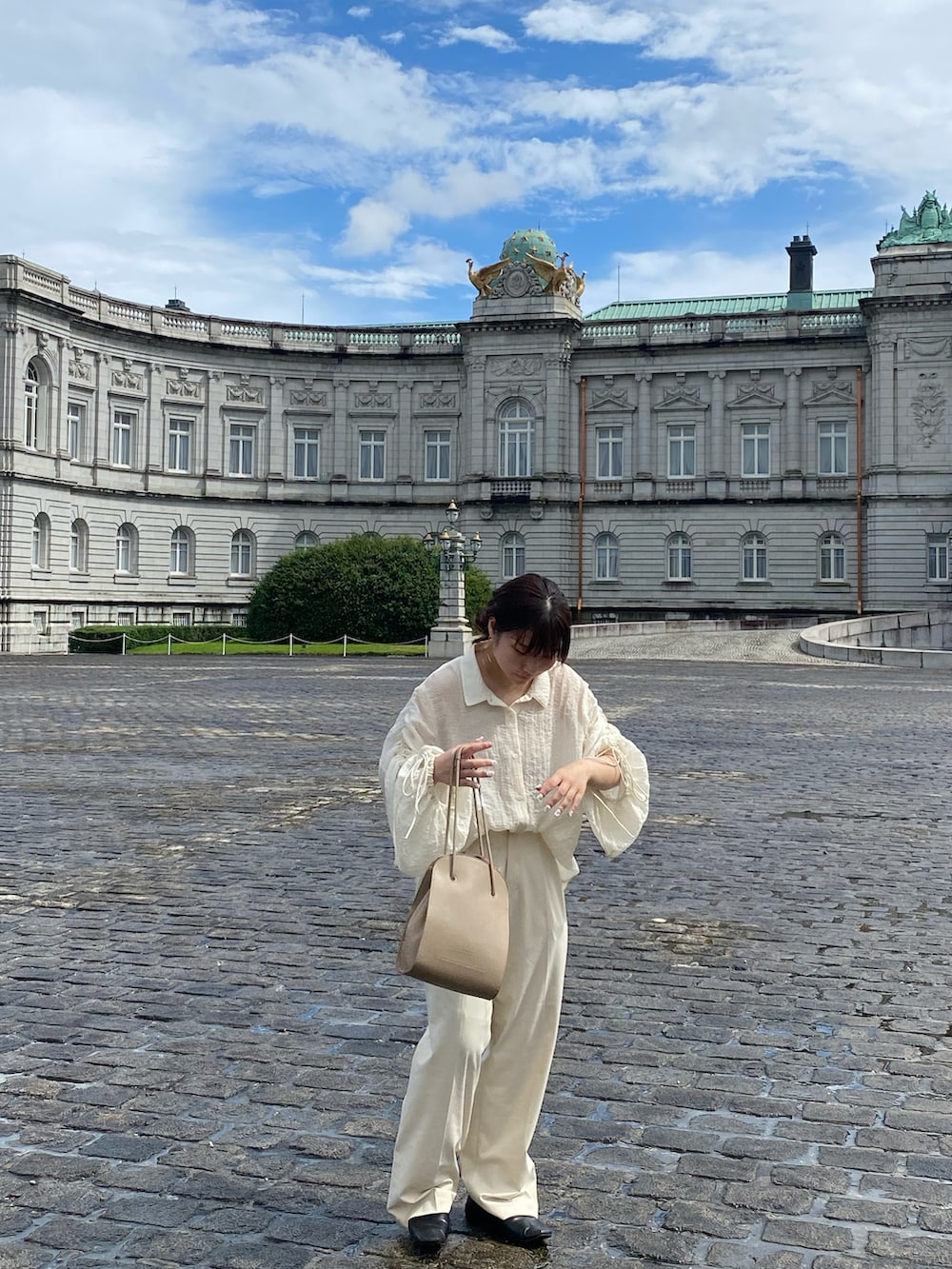 ベージュ系のトートバッグ、ホワイト系のシャツ/ブラウス、ホワイト系のスラックスを着用したレディースの夏コーディネートの2枚目の写真