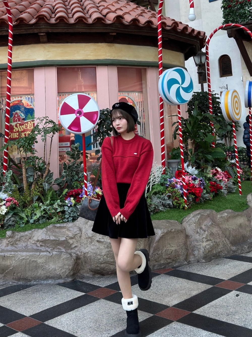 レッド系のニット/セーター、ブラック系のスカート、ブラウン系のハンドバッグを着用したレディースの冬コーディネートの3枚目の写真