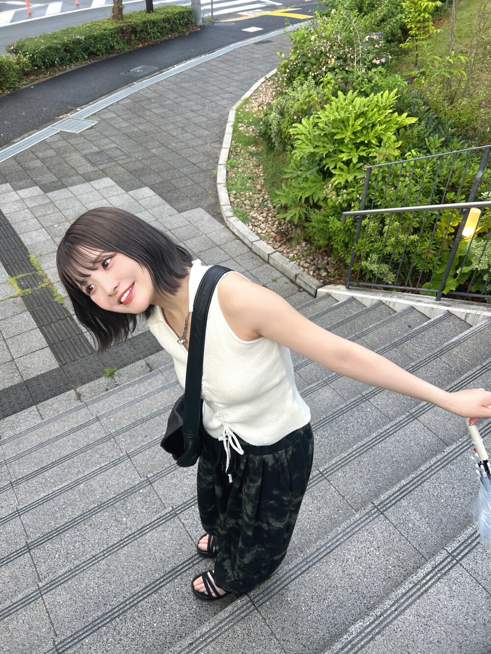 ブラック系のスウェットパンツ、ホワイト系のトップス、ブラック系のショルダーバッグを着用したレディースの夏コーディネートの2枚目の写真