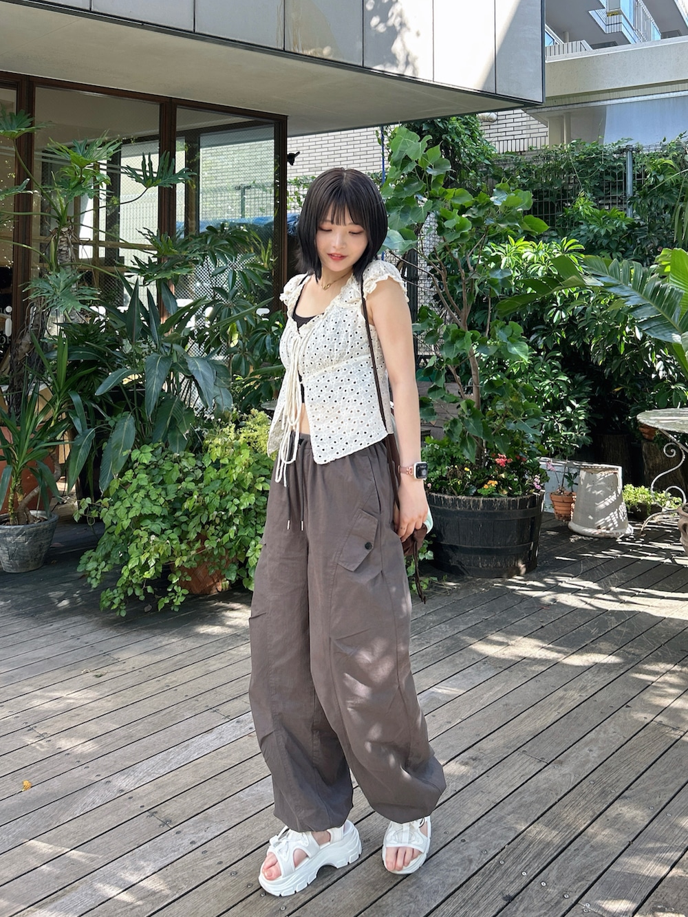 ブラウン系のバックパック/リュック、ホワイト系のトップスを着用したレディースの夏コーディネートの2枚目の写真