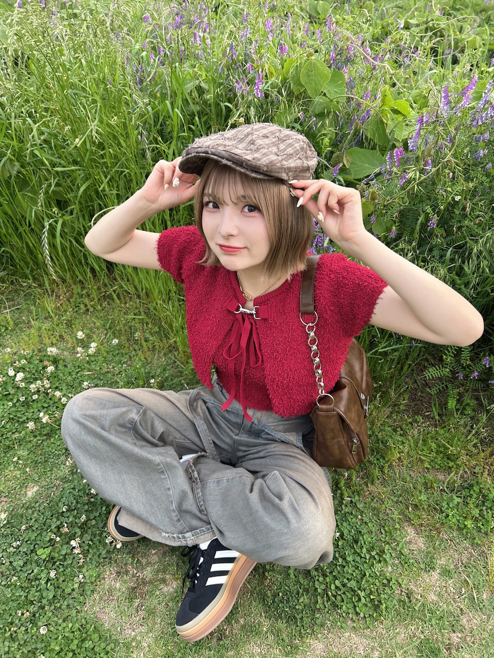 レッド系のアンサンブル、ブルー系のデニムパンツ、ブラック系のスニーカーを着用したレディースの春コーディネートの3枚目の写真