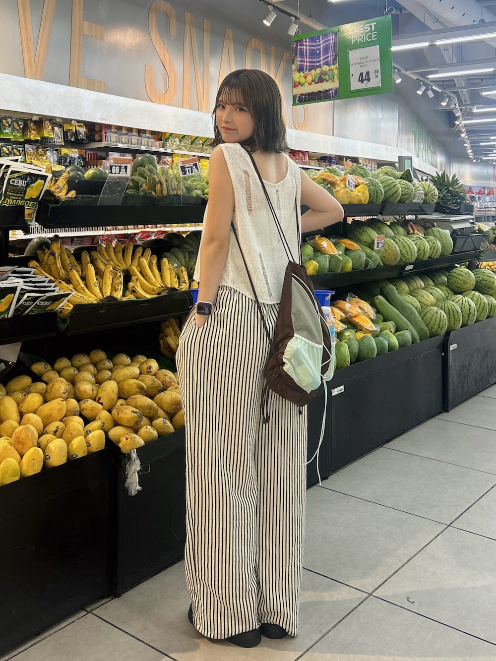 ブラウン系のバックパック/リュック、ホワイト系のスラックス、ホワイト系のベストを着用したレディースの夏コーディネートの2枚目の写真