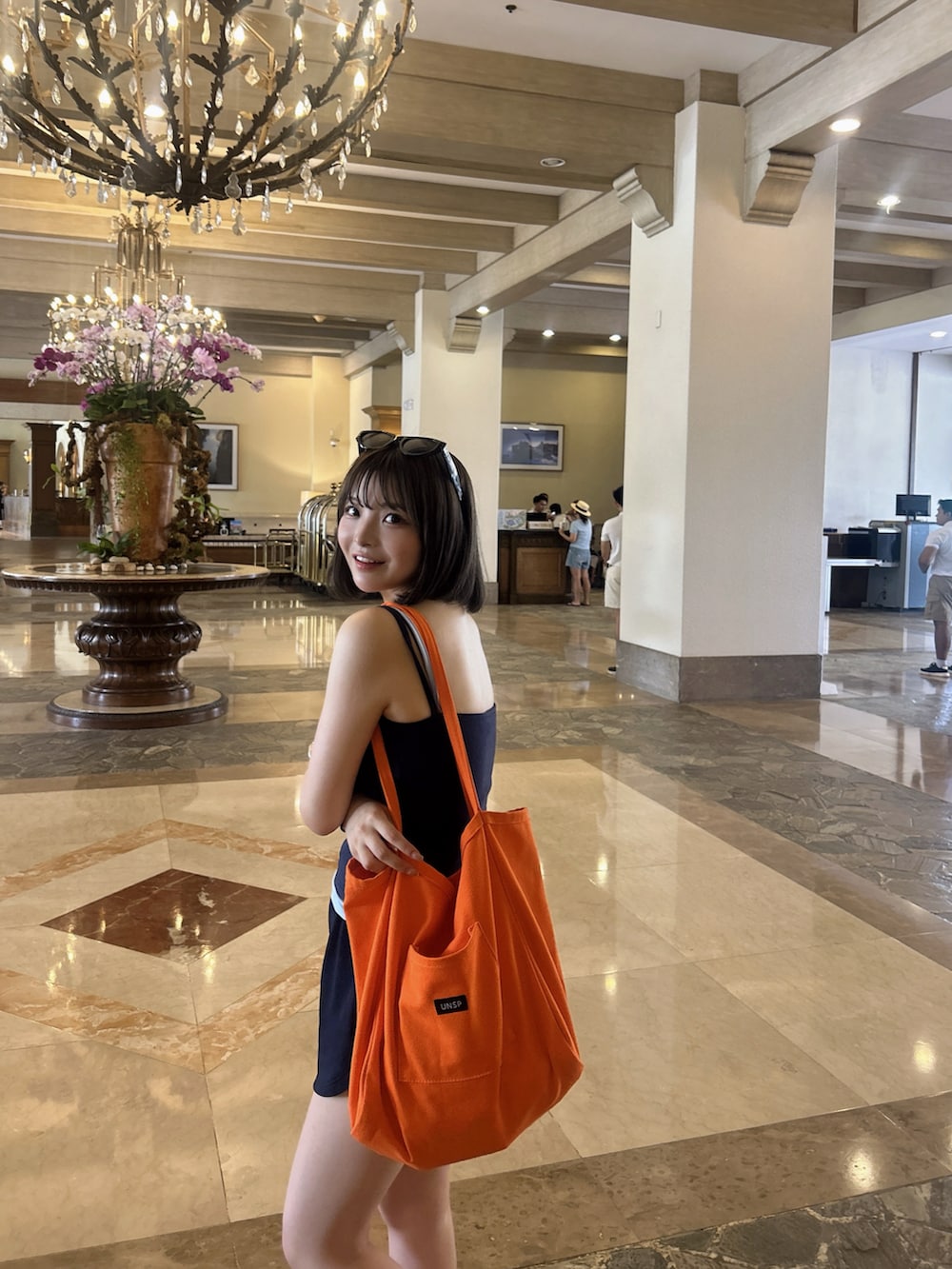 ブルー系のキャミソール、オレンジ系のトートバッグを着用したレディースの夏コーディネートの4枚目の写真