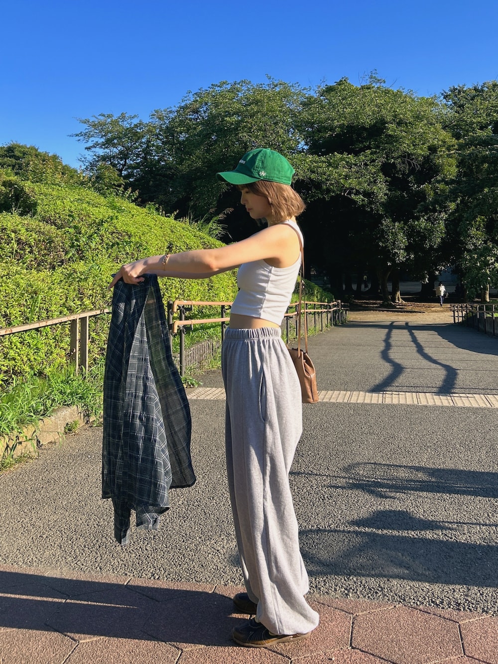 ホワイト系のタンクトップ、ブラウン系のスニーカー、グリーン系のキャップを着用したレディースの夏コーディネートの3枚目の写真