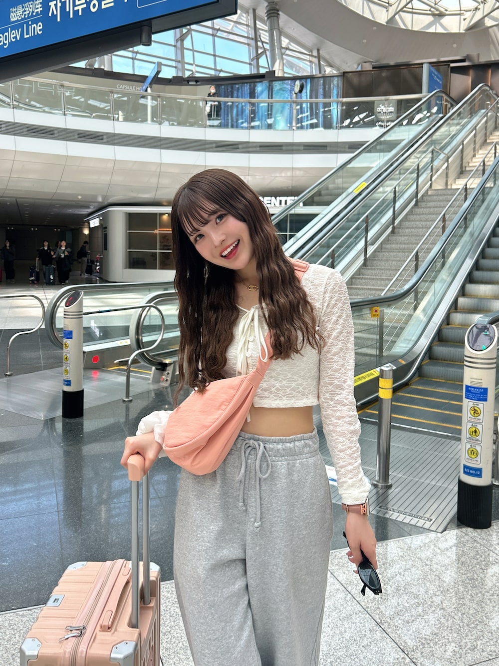 ピンク系のショルダーバッグ、ピンク系のスーツケース/キャリーバッグ、ピンク系のスニーカーを着用したレディースの春コーディネートの2枚目の写真