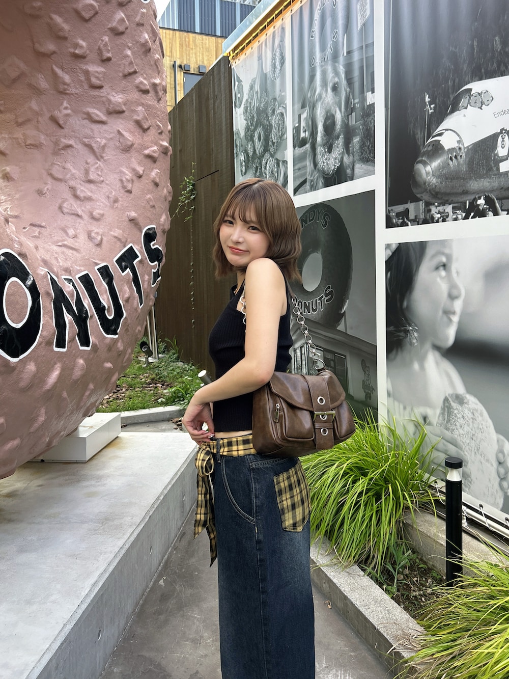 イエロー系のスニーカー、ブラウン系のハンドバッグ、ブラック系のタンクトップを着用したレディースの夏コーディネートの3枚目の写真