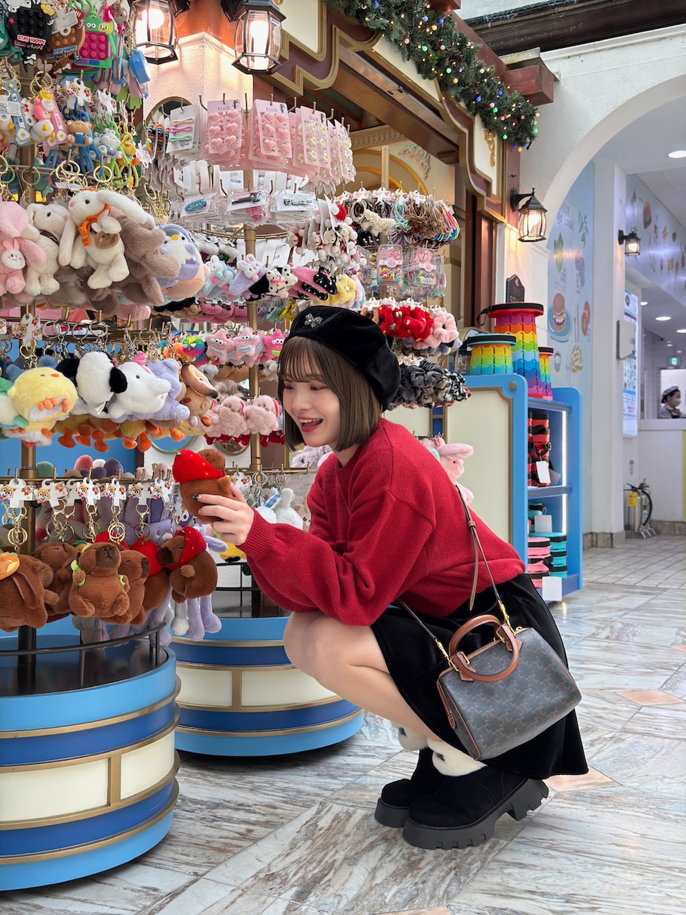 レッド系のニット/セーター、ブラック系のスカート、ブラウン系のハンドバッグを着用したレディースの冬コーディネートの2枚目の写真