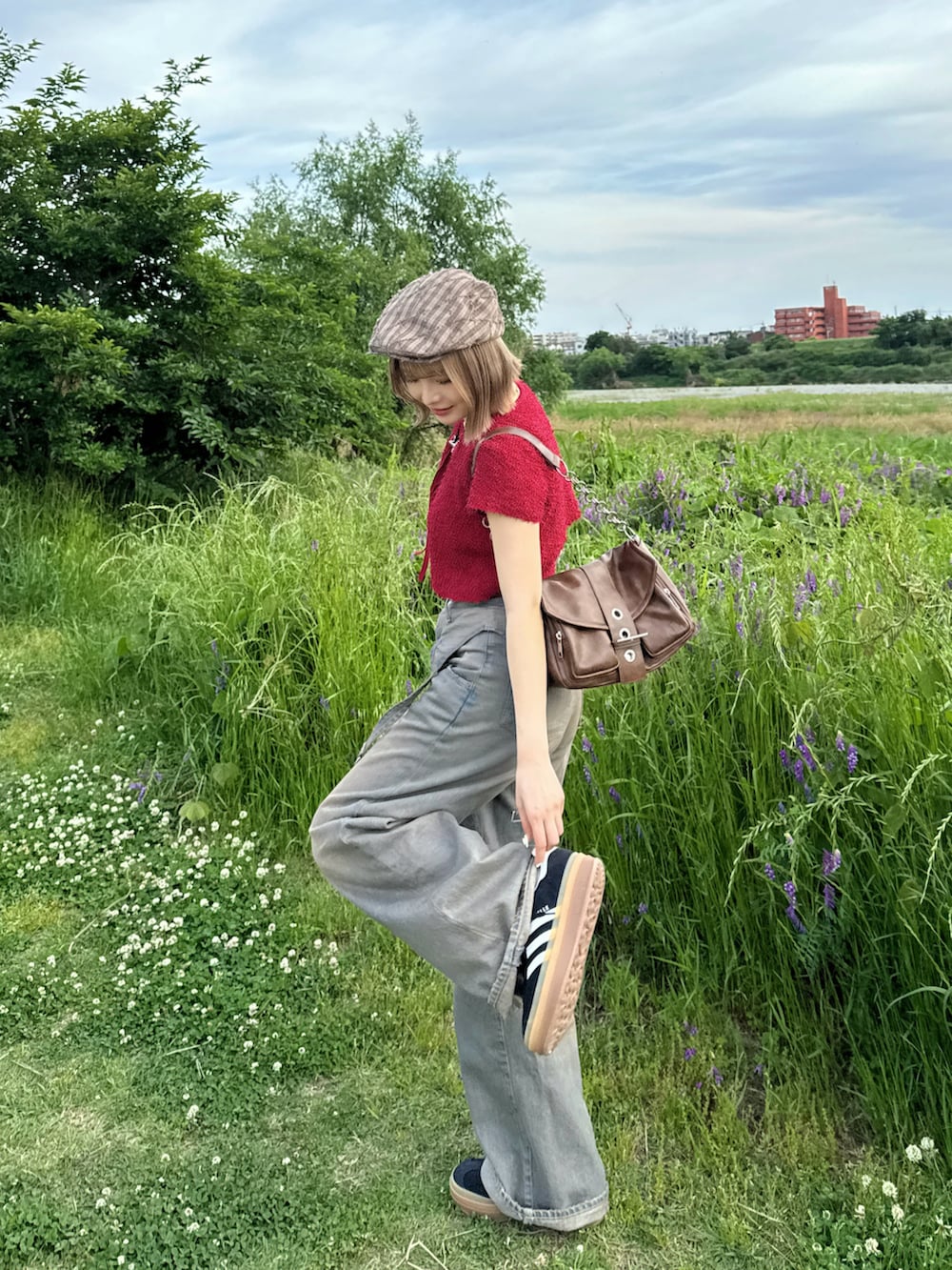 レッド系のアンサンブル、ブルー系のデニムパンツ、ブラック系のスニーカーを着用したレディースの春コーディネートの2枚目の写真