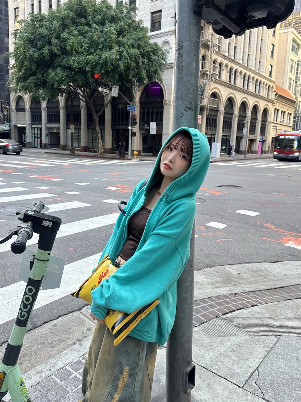 グリーン系のパーカー、ホワイト系のスニーカー、ブルー系のデニムパンツを着用したレディースの冬コーディネートの2枚目の写真