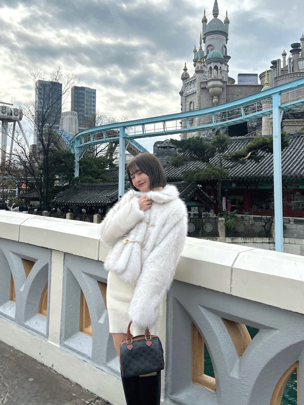 ホワイト系のジャケット/アウター、ブラック系のブーツ、ブラウン系のトートバッグを着用したレディースの冬コーディネートの2枚目の写真