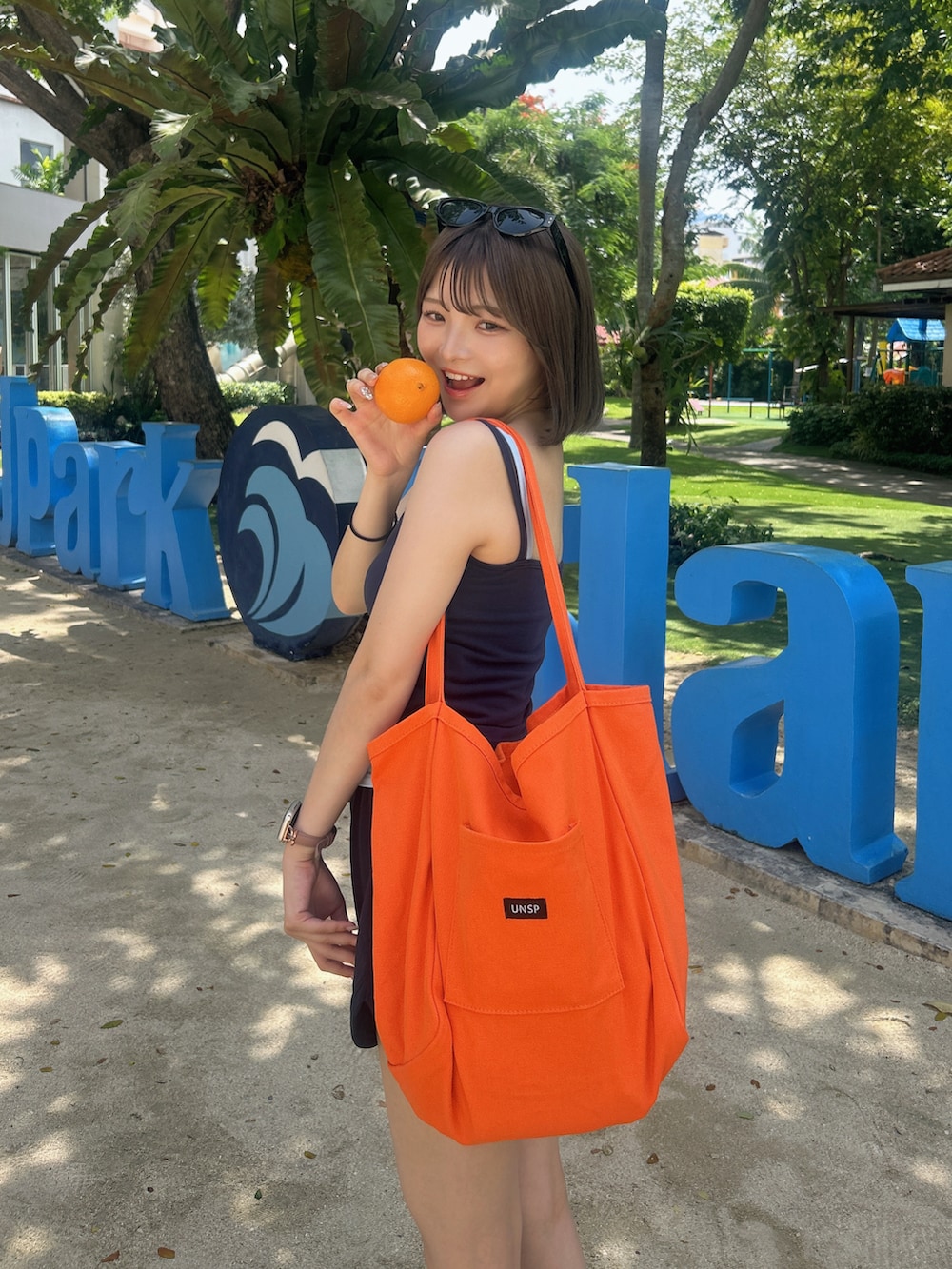 ブルー系のキャミソール、オレンジ系のトートバッグを着用したレディースの夏コーディネートの2枚目の写真