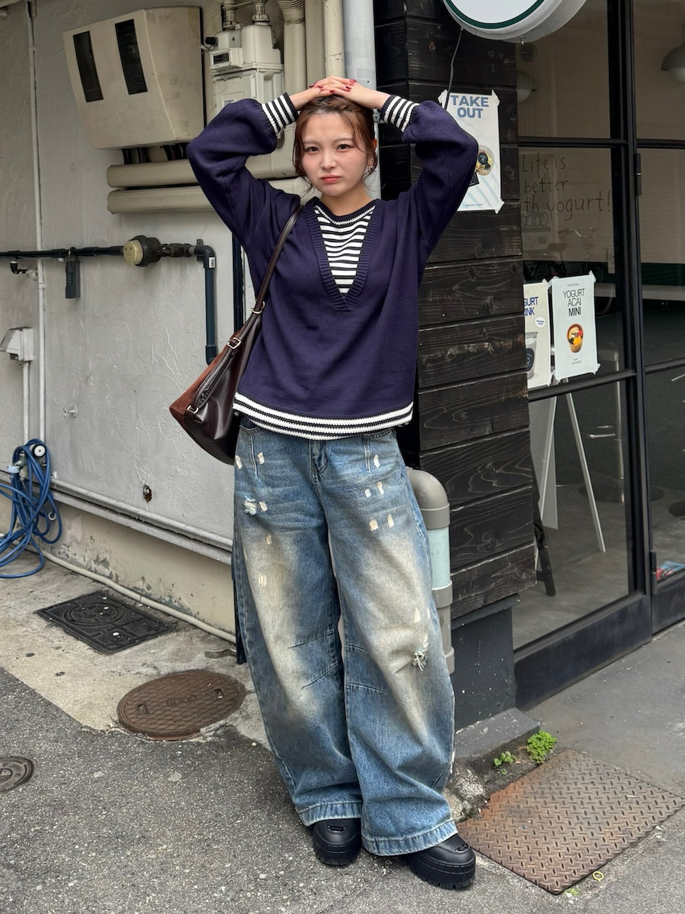 ブラック系のスニーカー、ブルー系のデニムパンツ、ブルー系のニット/セーターを着用したレディースの春コーディネートの3枚目の写真