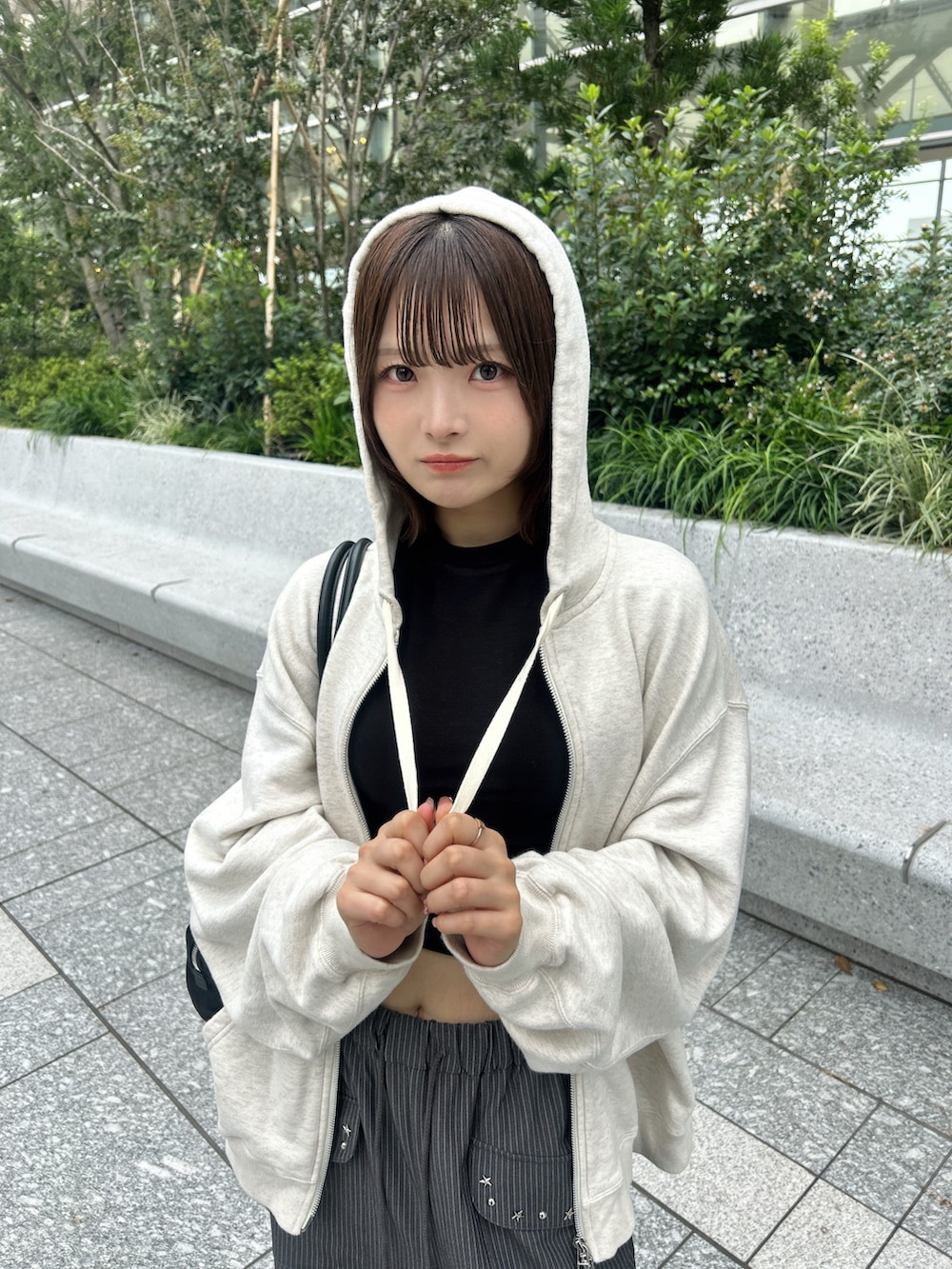 グレー系のスラックス、ベージュ系のパーカー、ブラック系のトートバッグを着用したレディースの秋コーディネートの3枚目の写真