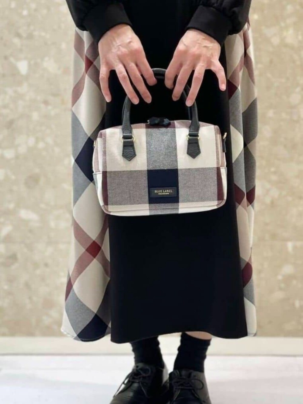 ブラック系のワンピース、ベージュ系のボストンバッグ、ホワイト系のマフラーを着用したレディースの秋コーディネートの3枚目の写真