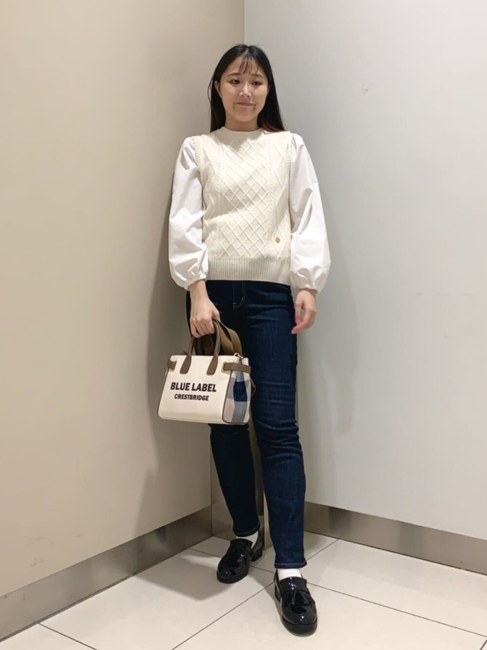 ブラック系のローファー、ホワイト系のトートバッグ、ブルー系のデニムパンツを着用したレディースの秋コーディネートの4枚目の写真