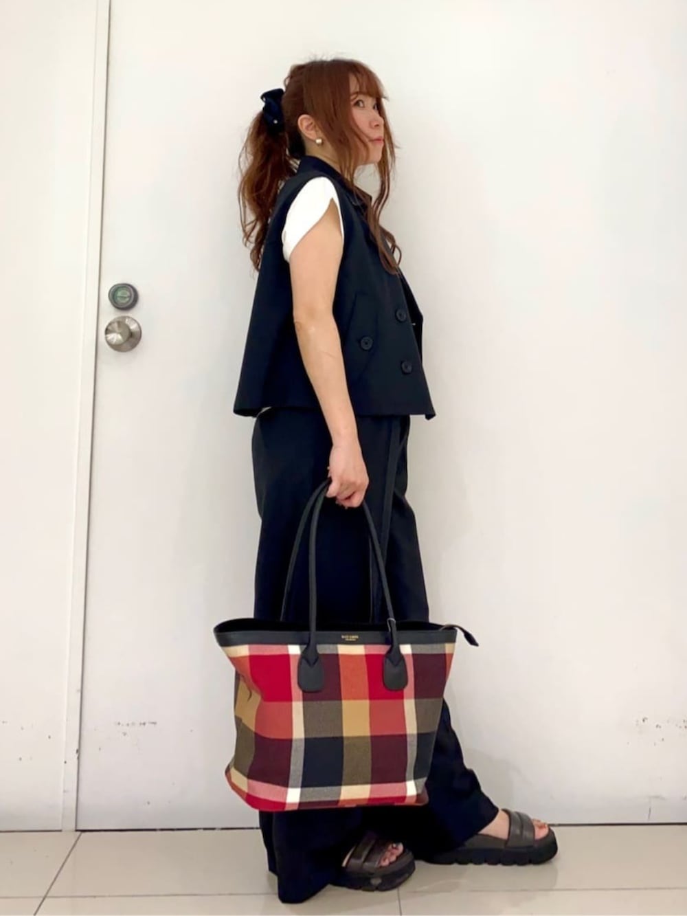 ブラック系のベスト、ブラック系のその他パンツ、レッド系のトートバッグを着用したレディースの夏コーディネートの2枚目の写真