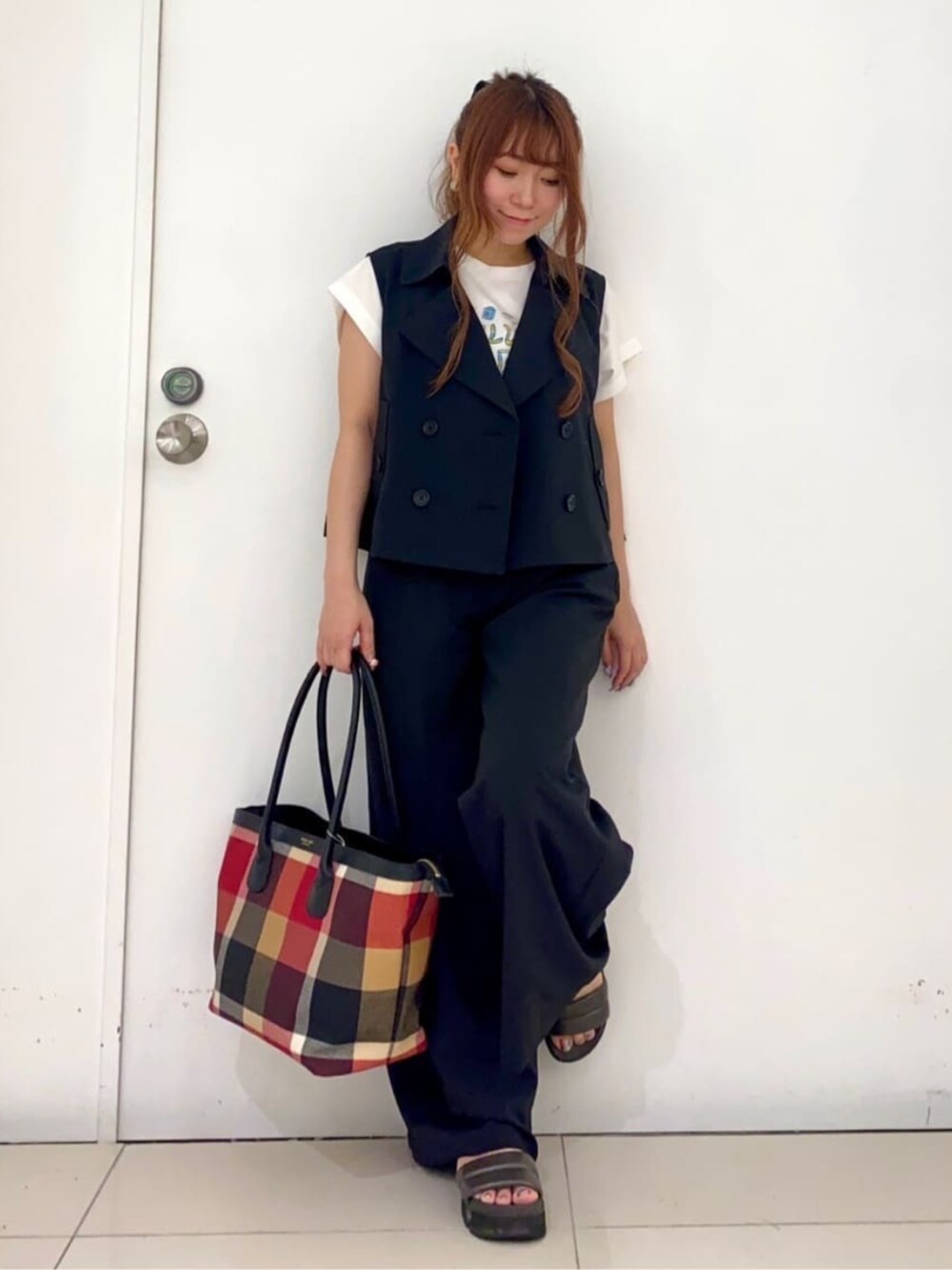 ブラック系のベスト、ブラック系のその他パンツ、レッド系のトートバッグを着用したレディースの夏コーディネートの3枚目の写真