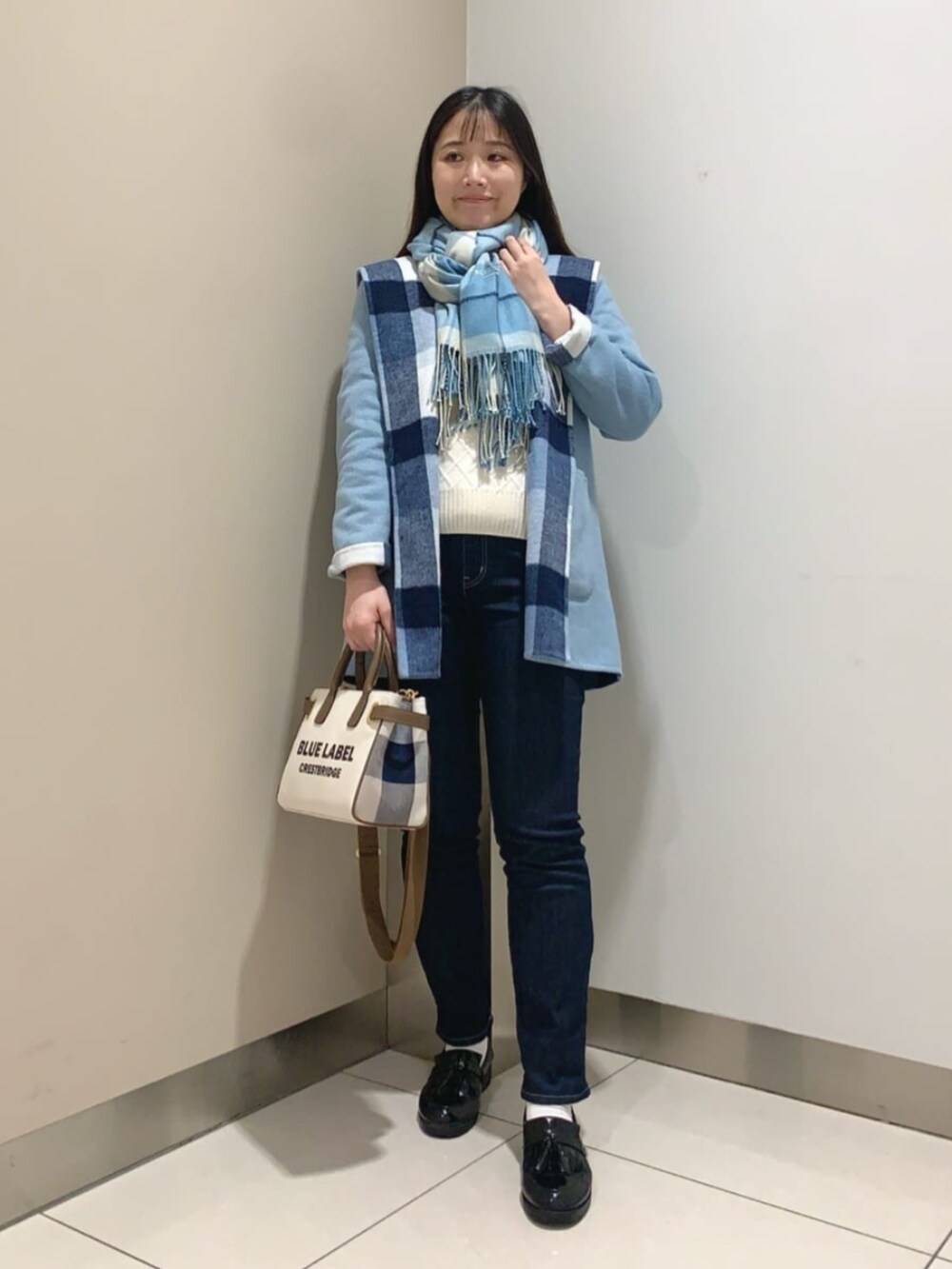 ブラック系のローファー、ホワイト系のトートバッグ、ブルー系のデニムパンツを着用したレディースの秋コーディネートの2枚目の写真