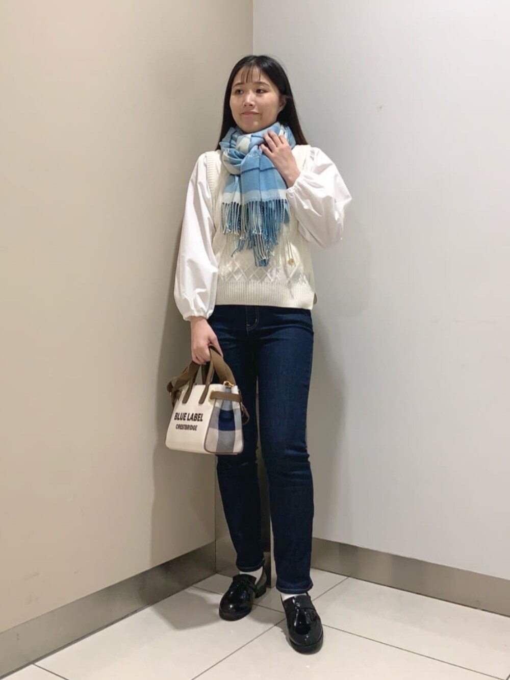 ブラック系のローファー、ホワイト系のトートバッグ、ブルー系のデニムパンツを着用したレディースの秋コーディネートの3枚目の写真